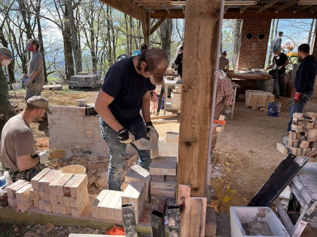 Heater Mason building a masonry heater, tapping a brick with a trowel