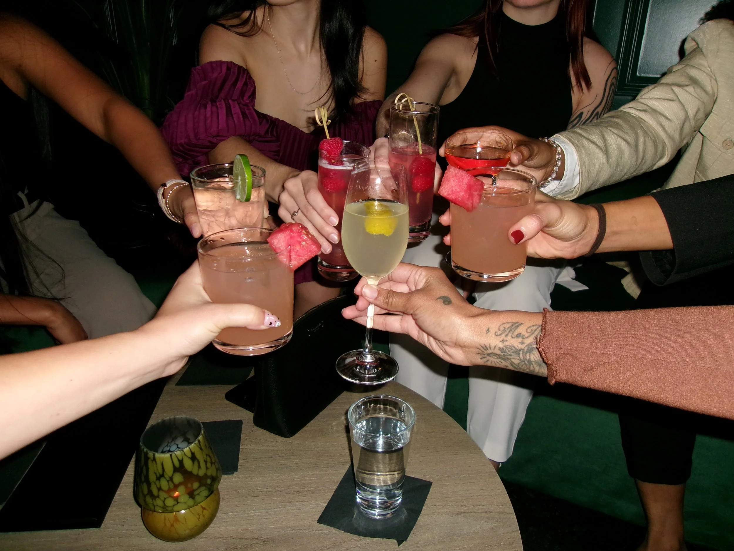 Group of people clinking glasses with cocktails at a table