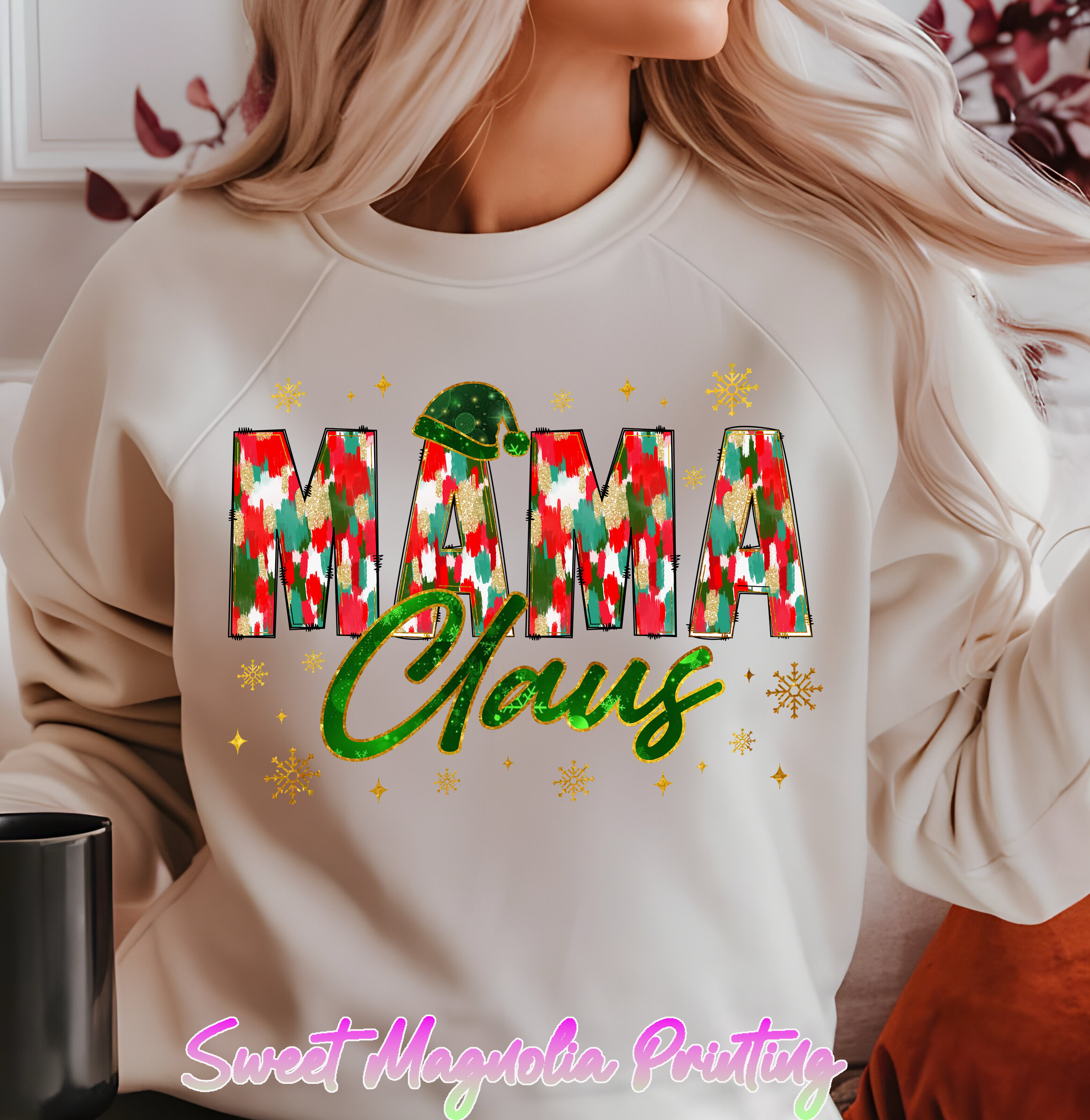 Colorful text reads "MAMA Claus," adorned with a green Santa hat and golden snowflakes against a festive background | Christmas Transfer | Sweet Magnolia Printing