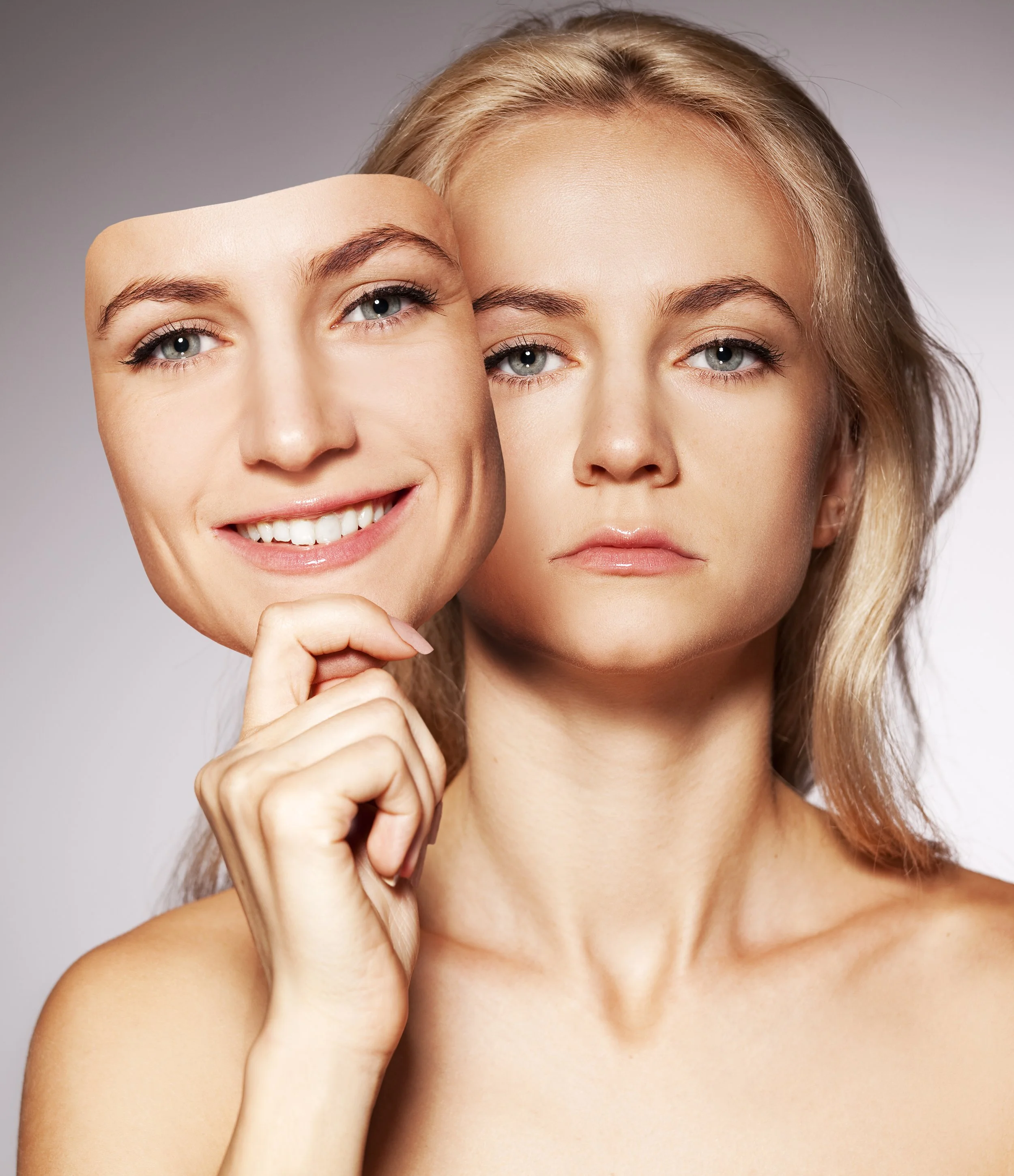 covert narcissistic abuse: Woman holding up mask of her face that is smiling over her real face that has a scowl illustrating covert narcissist