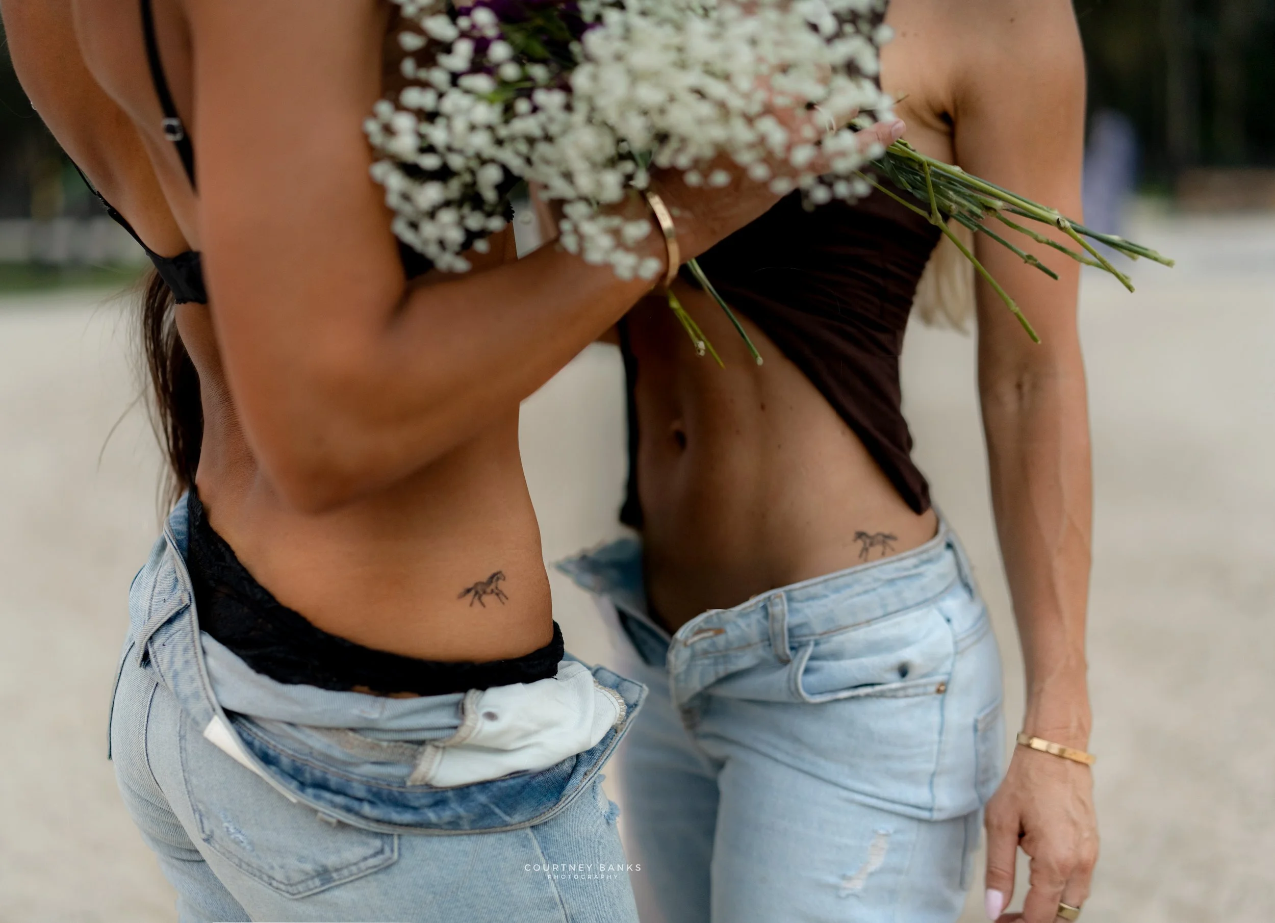 Two women with horse tattoos during a coastal cowgirl editorial at White Oak Equestrian in Southwest Ranches, Florida.