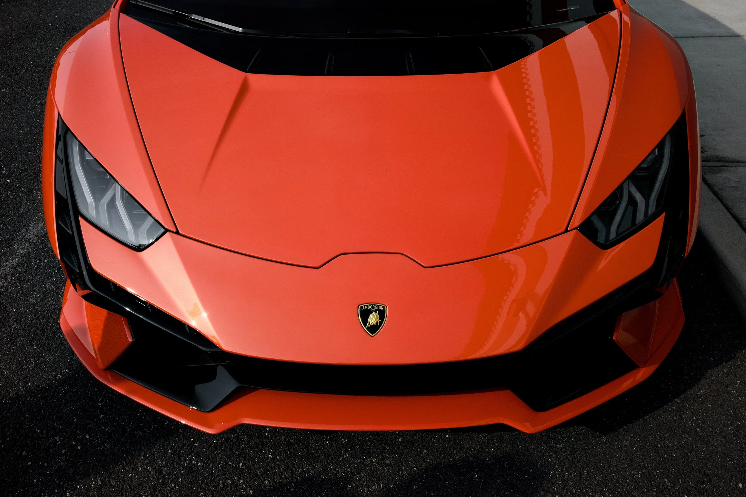 A red Lamborghini sports car viewed from above, showing the front of the car with its sleek design and angular headlights.