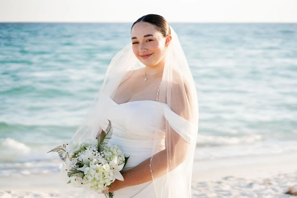 bride smiling at camera with gulf waves and soft sand as the backdrop along 30A's natural gulf coast after eloping in florida