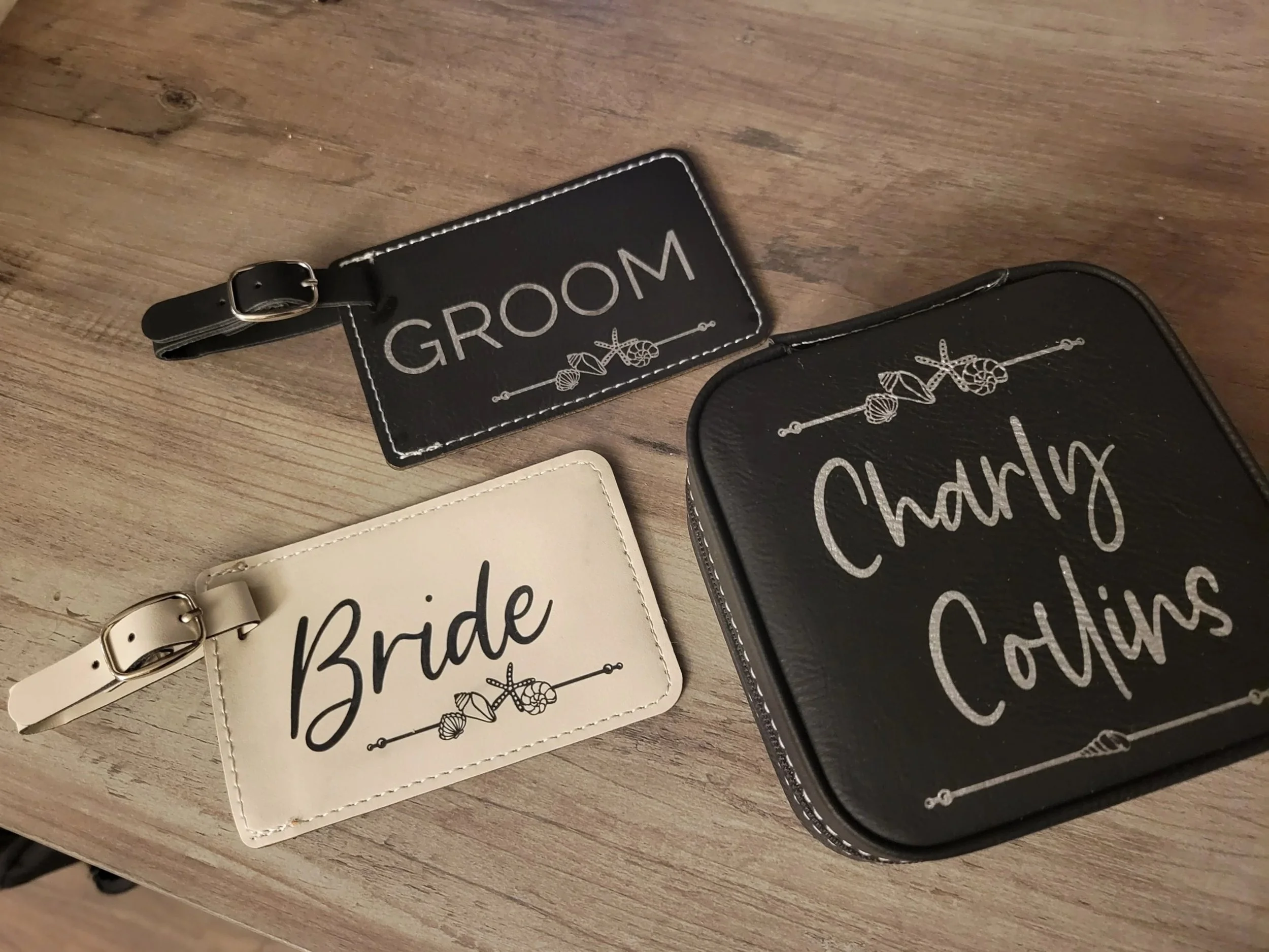 Wedding accessories including a black groom luggage tag, a white bride luggage tag, and a black Charlie Colins box with wedding-related designs.