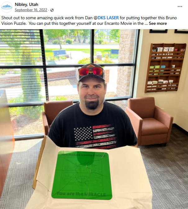 Dan the owner of DKS Laser,  sitting at a table with a green puzzle piece that says 'You are the MIRACLE.' in a room with large windows, outside view of greenery, and brown chairs.