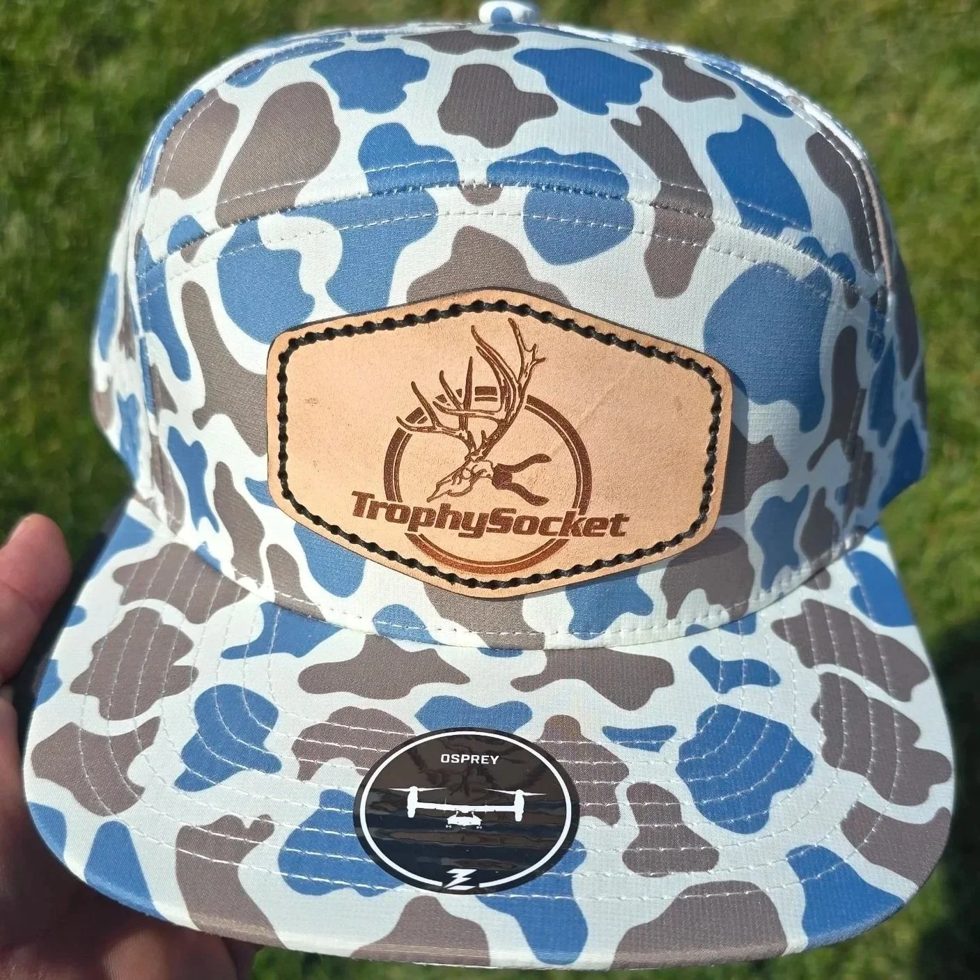 Trophy Socket Logo on leather patch sewn on to an Osprey 7 panel hat that is a blue/grey & white camo