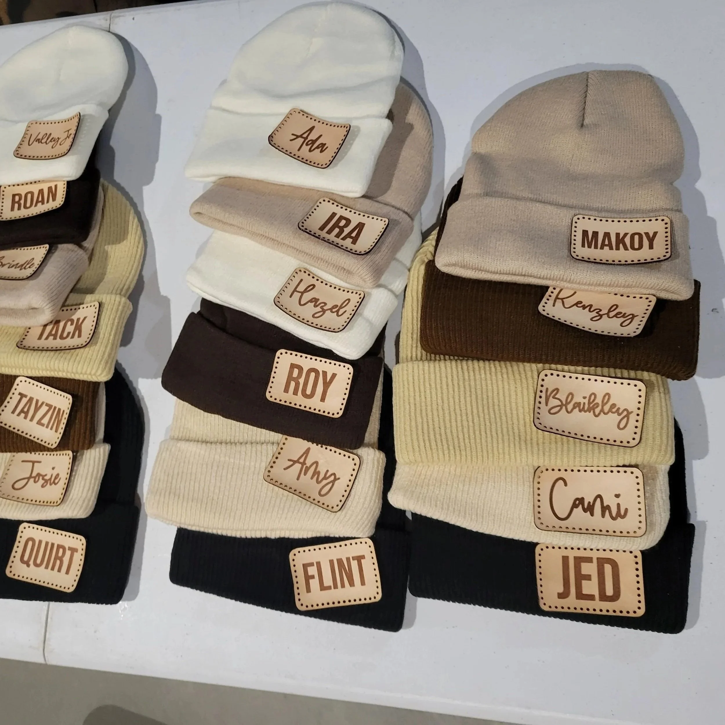 Patches from the previous picture that have been laid out on an assortment of colors of headwear beanies. Lots of different sizes and colors.