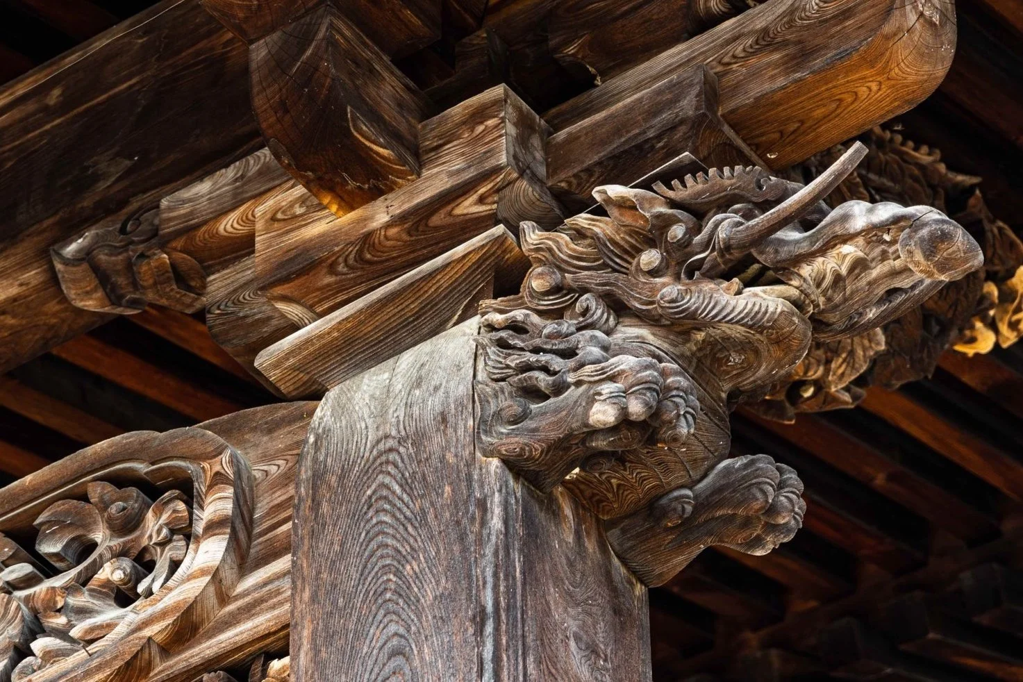 Intricate wooden dragon carving on a traditional architectural beam.