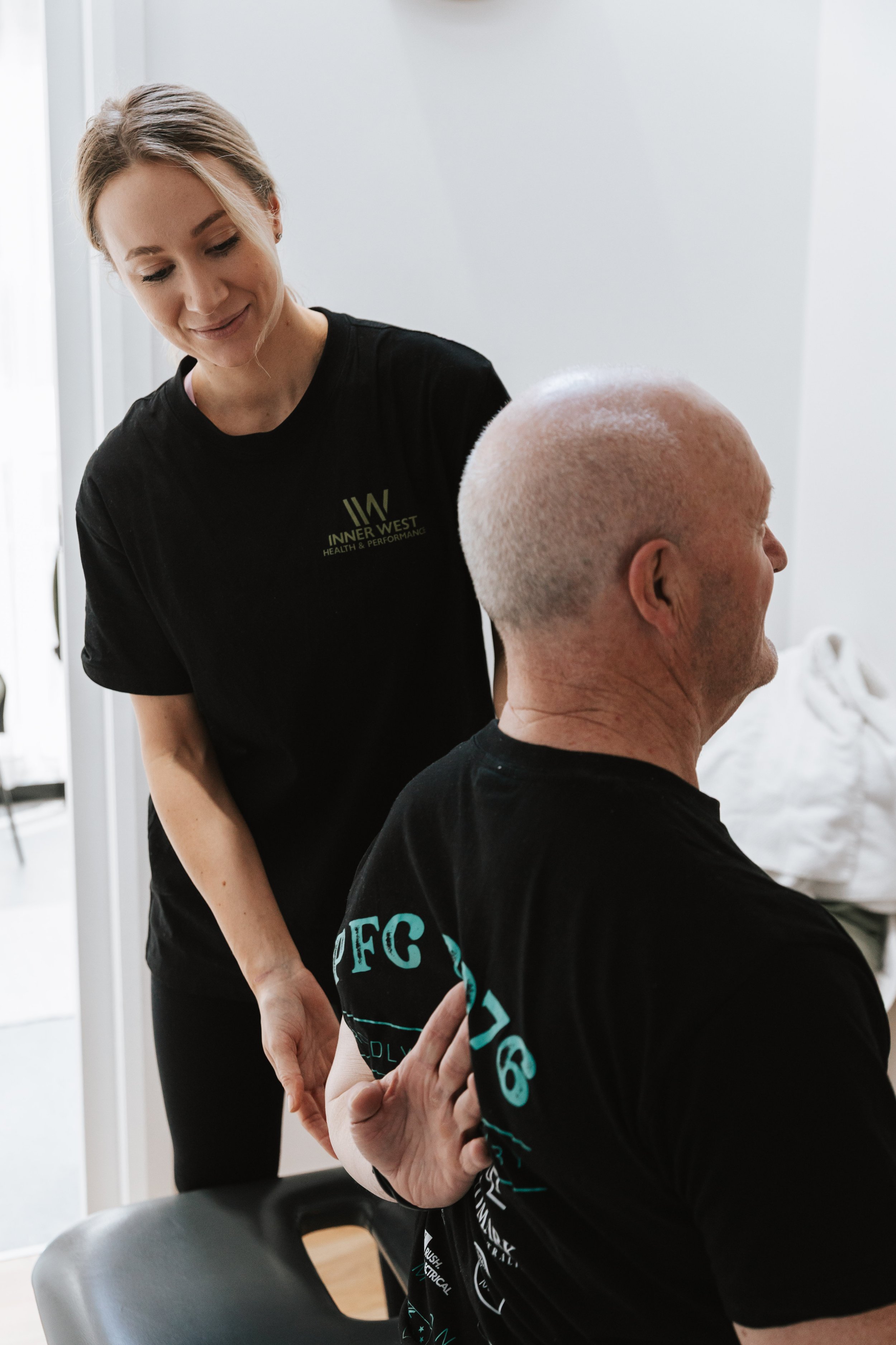 Mia, Myotherapist assessing a patients shoulder range of motion whilst they are seated on a treatment table