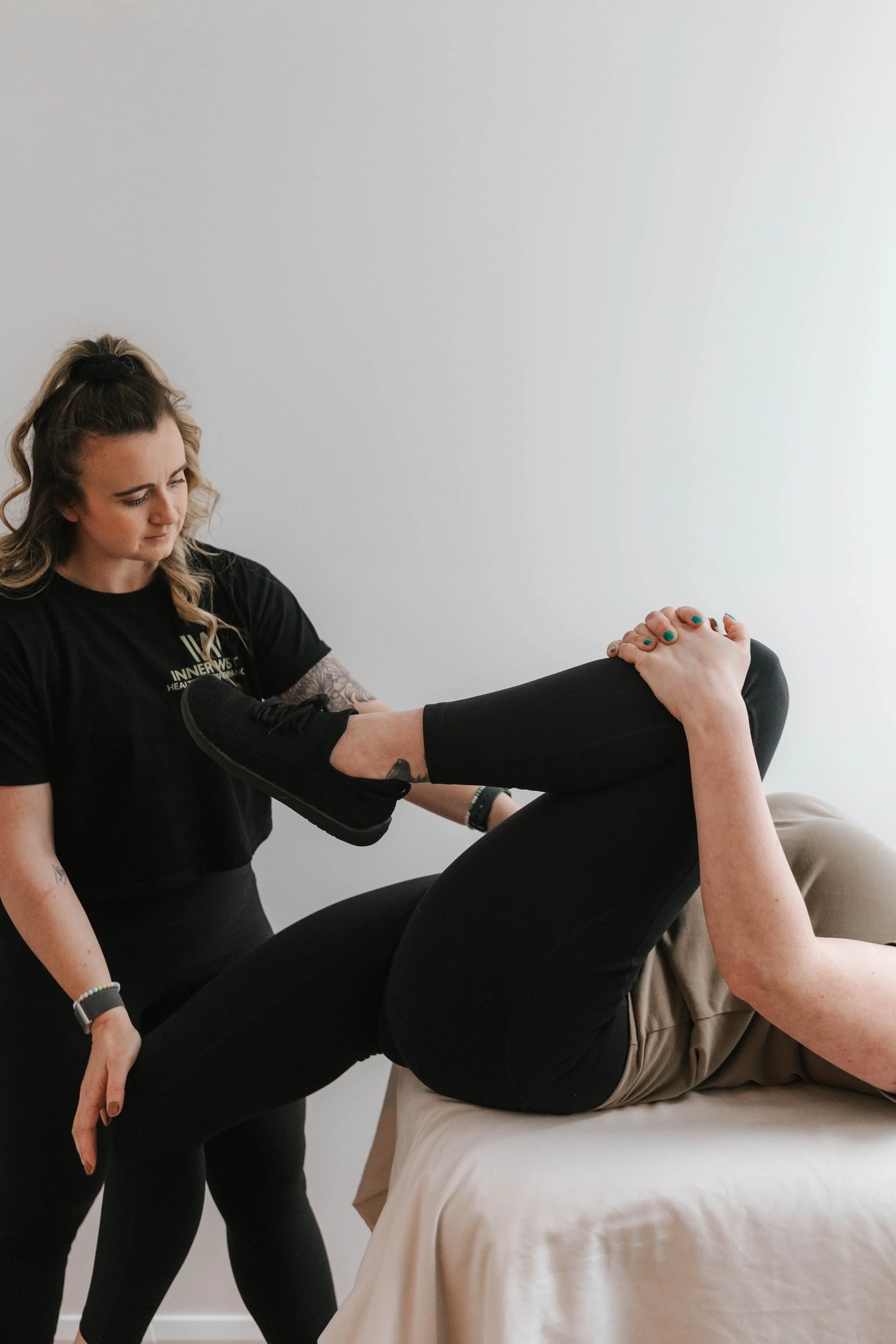 Kirby, Myotherapist assessing a patients hip range of motion on the edge of a treatment table