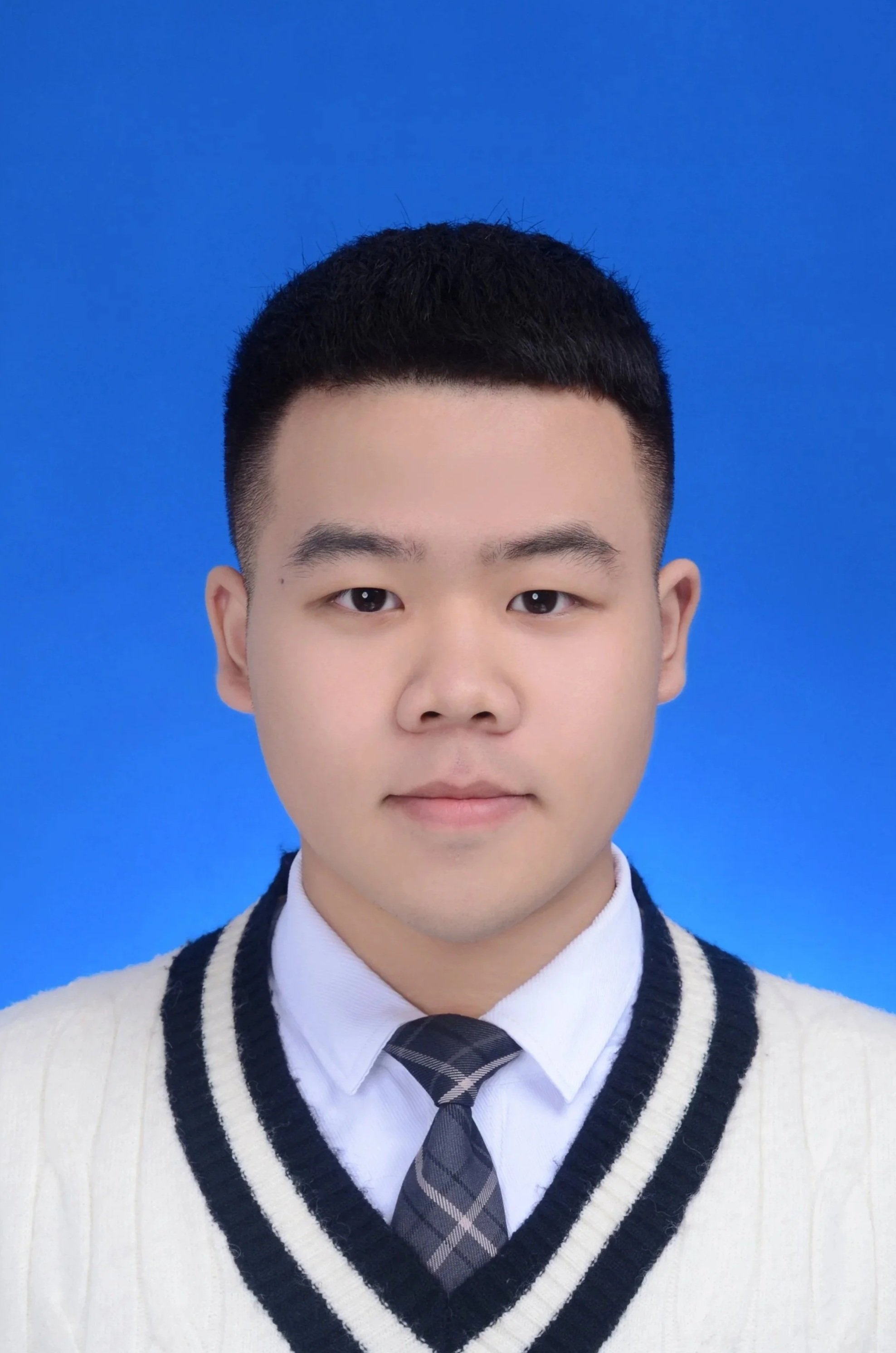 A young man with glasses wearing a white shirt and backpack taking a selfie indoors, standing in front of a wooden door.