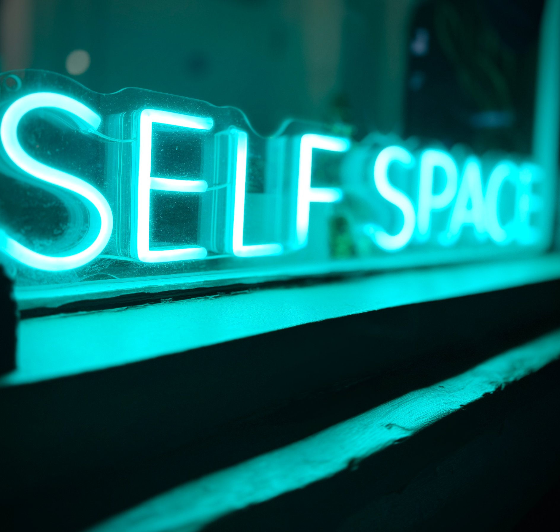 Neon sign reading 'SELF SPACE' in blue lighting.