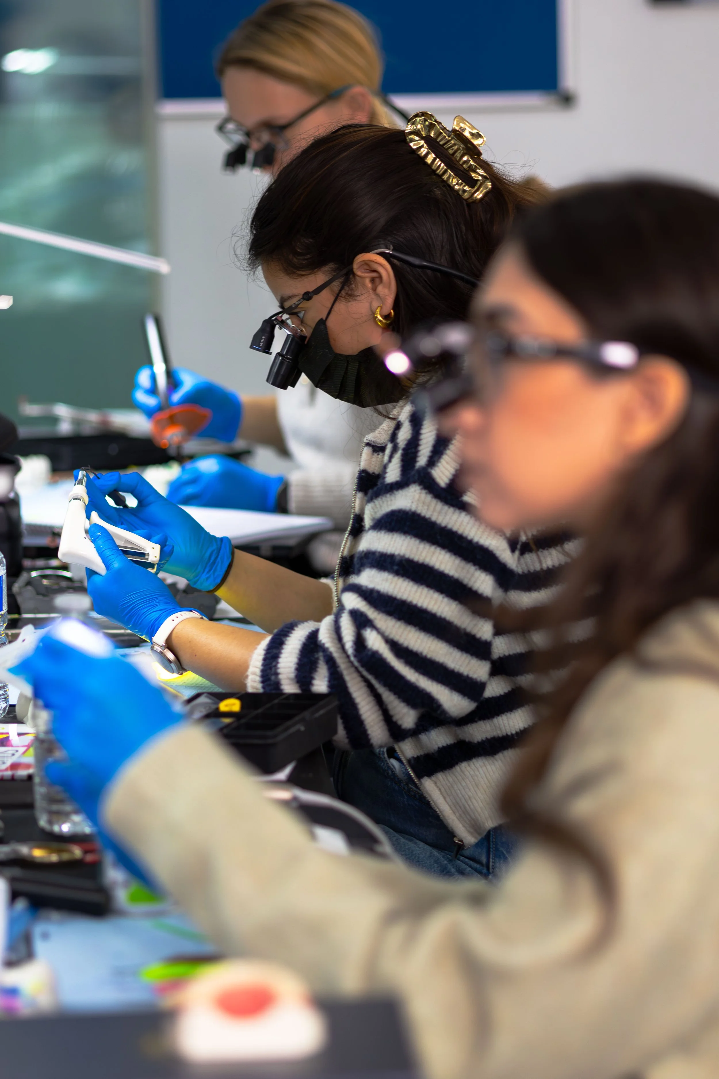 Scientists working in a laboratory, wearing magnifying glasses and face masks, focusing on experiments with lab equipment and tools.