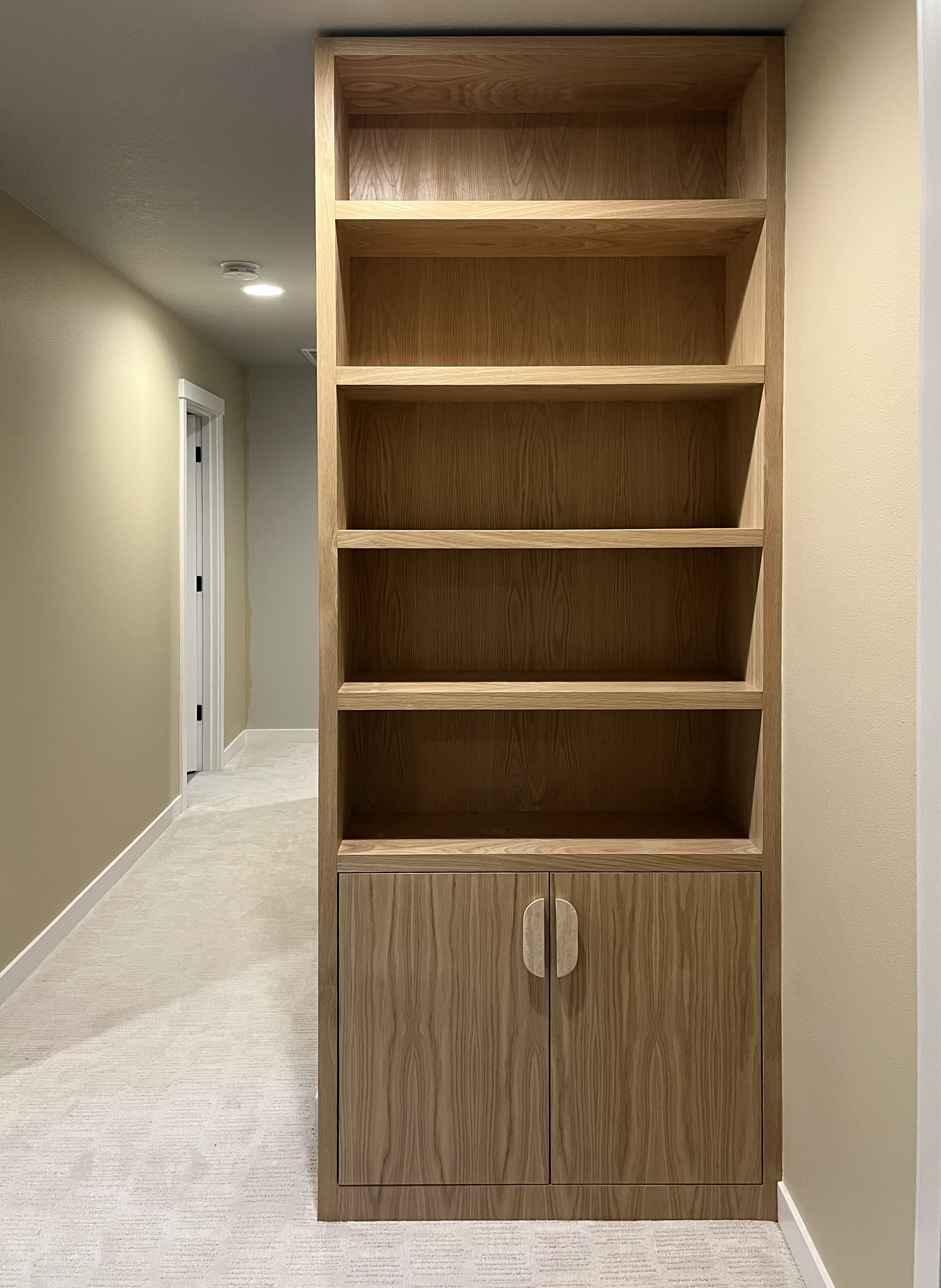 Custom plain sawn white oak bookcase with cabinet on a stair landing.