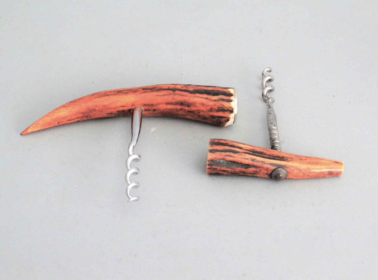 An early to mid 20th-Century continental set of two natural antler corkscrew bottle openers. The are bone antler with a metal screw. They are functional and decorative. Located in Austin, Texas.