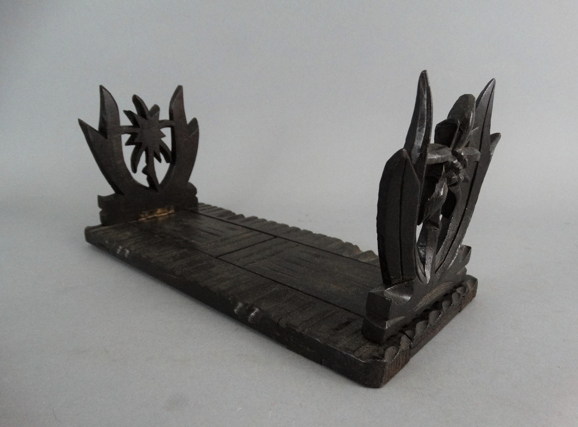 An early 20th-century carved telescoping Black Forest book slide. It has carved palm trees on both ends. Located in Austin, Texas.