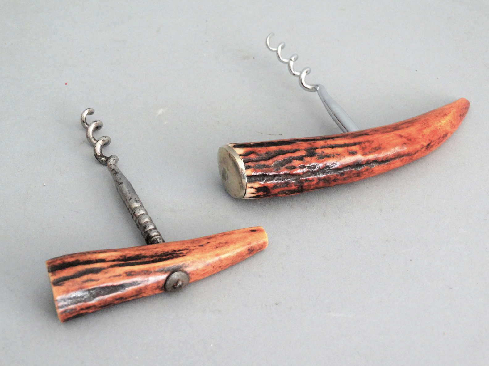 An early to mid 20th-Century continental set of two natural antler corkscrew bottle openers. The are bone antler with a metal screw. They are functional and decorative. Located in Austin, Texas.