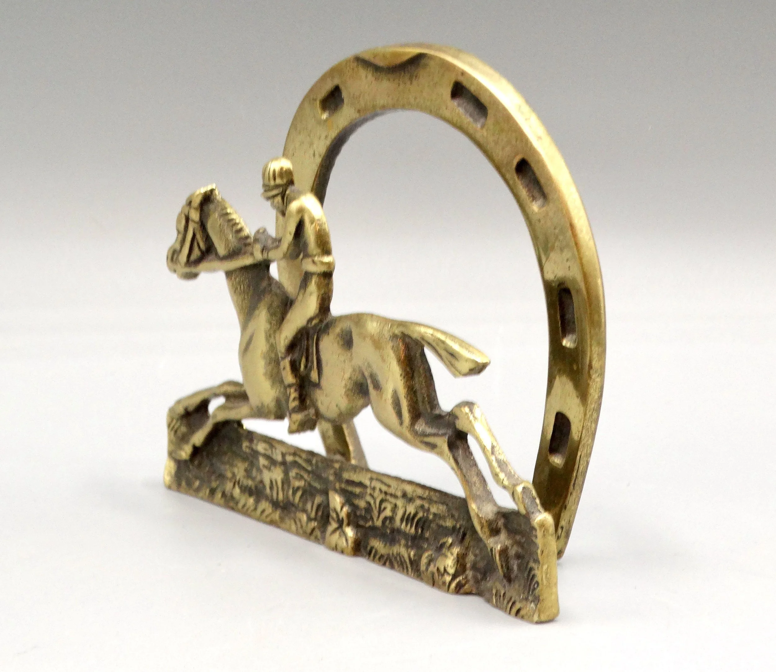 A circa 1930s English solid brass letter rack or napkin holder. It features a racing jockey with a decorative horse shoe in the back. Located in Austin, Texas.