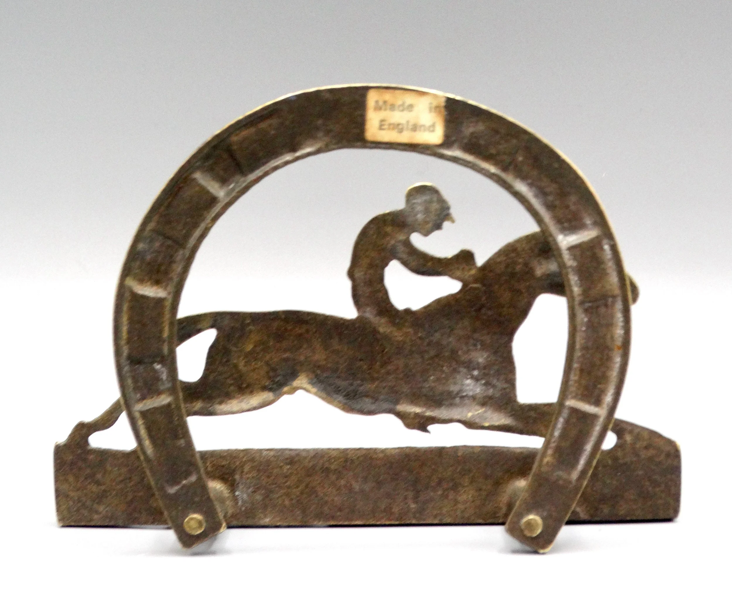 A circa 1930s English solid brass letter rack or napkin holder. It features a racing jockey with a decorative horse shoe in the back. Located in Austin, Texas.