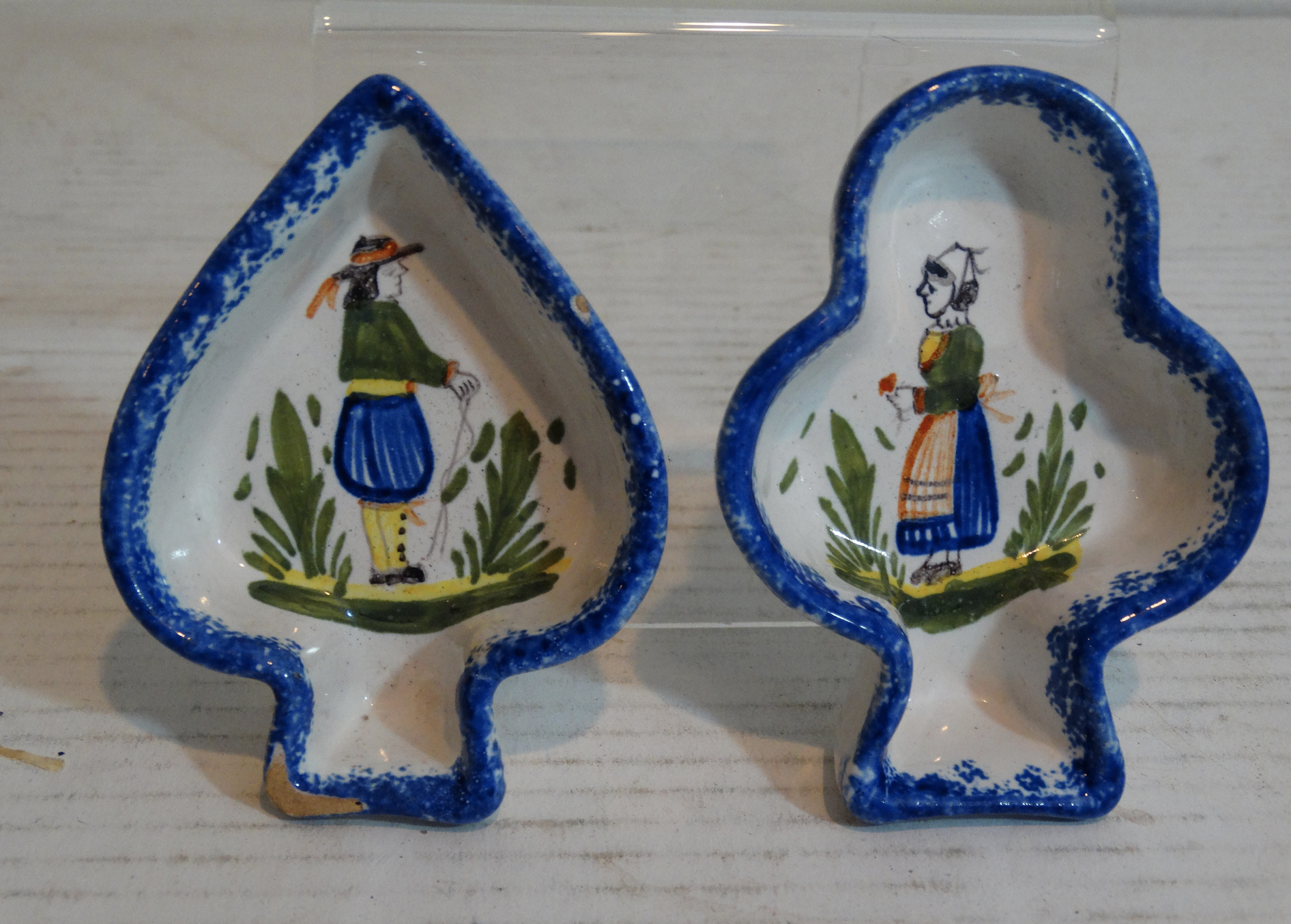 Set of two charming French faience Quimper butter pats in spade and club shapes with painted traditional Breton man and woman figures. Located in Austin, Texas.