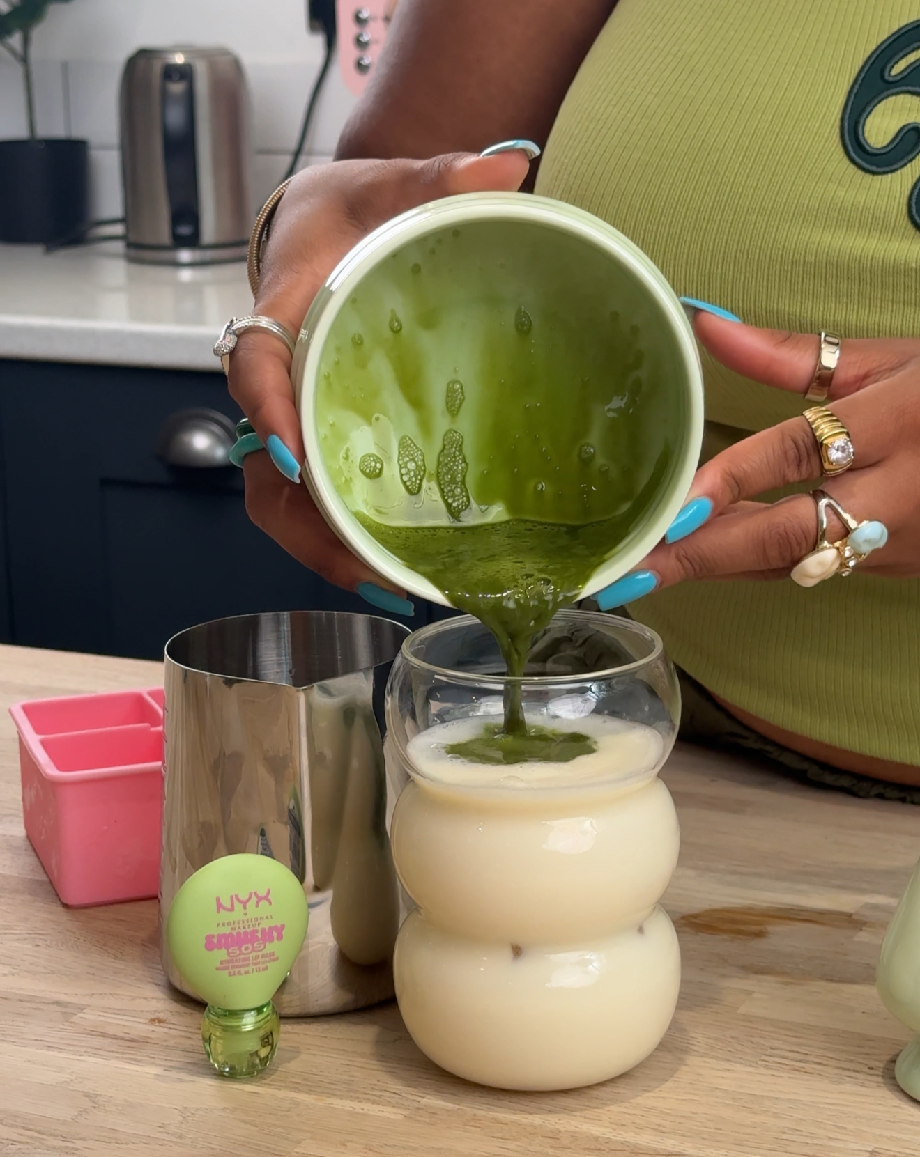 Close-up UGC shot of hands pouring matcha into a glass of milk next to a beauty product, filmed at LND Studio