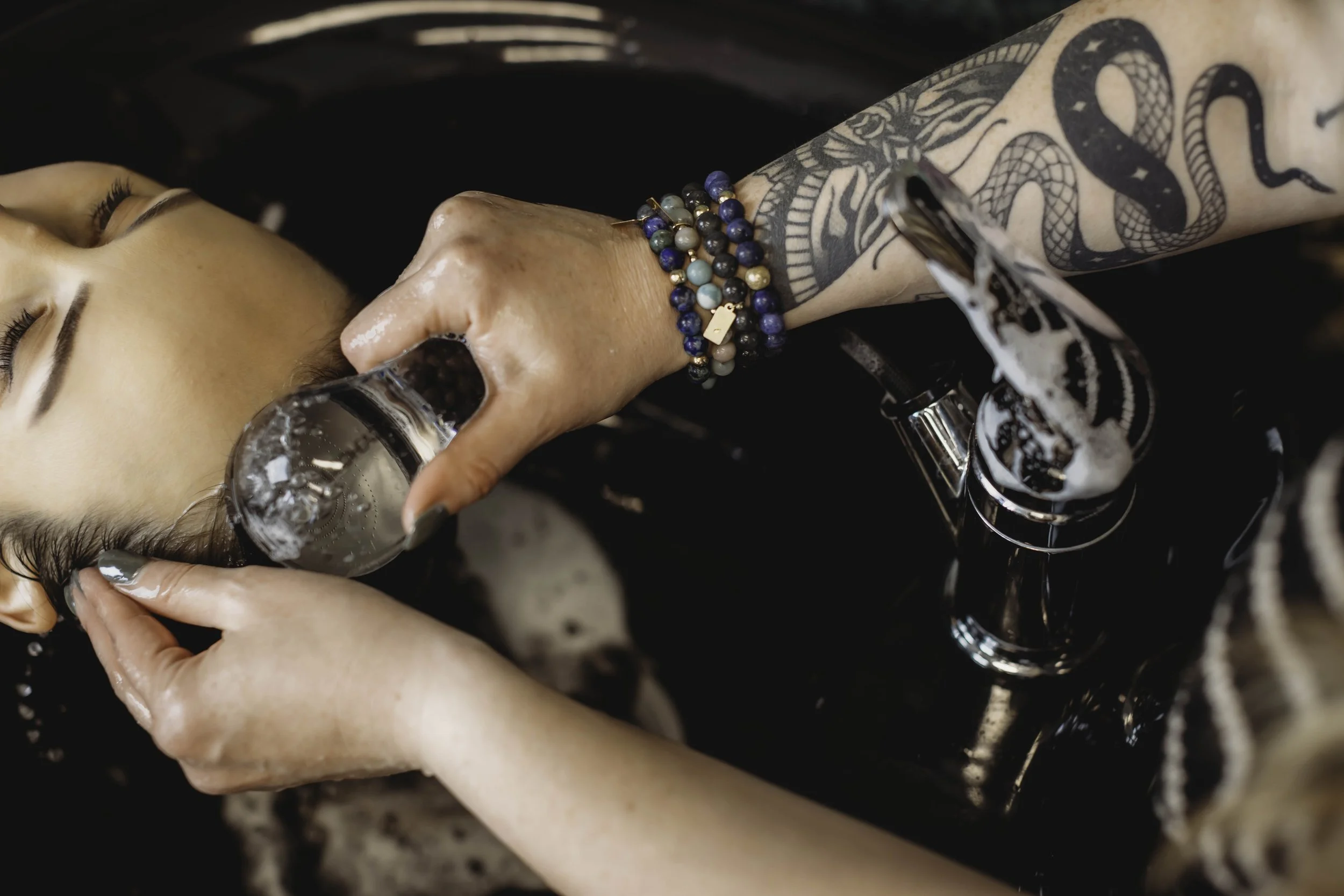 A woman with tattoos and bracelets receiving a scalp facial treatment at Holistic Hair by Kellyn in Superior/Boulder, Colorado.