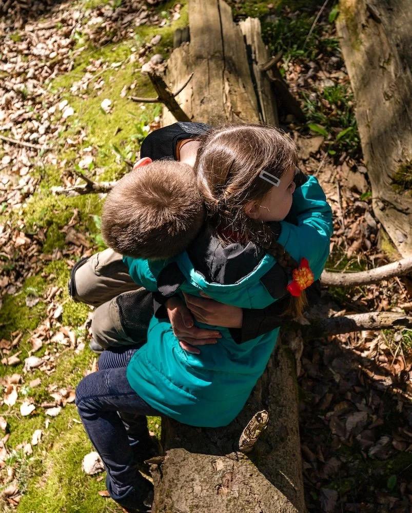 healthy siblings embracing outdoors in nature