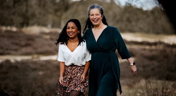 A happy mother and her adopted daughter from Cambodia walking and laughing outdoors, illustrating the lifelong bond formed through international adoption charity programs.