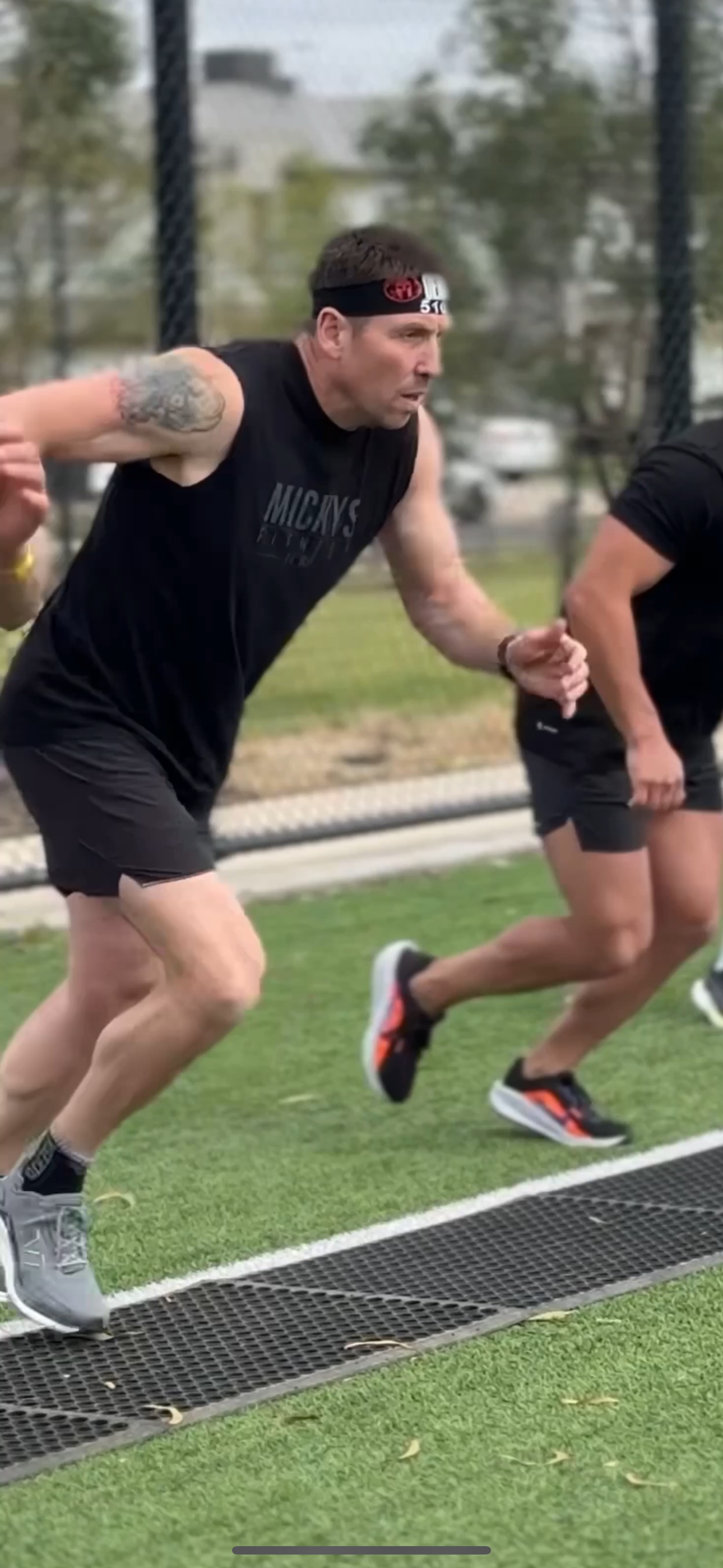 People running on a sports field, wearing athletic gear.