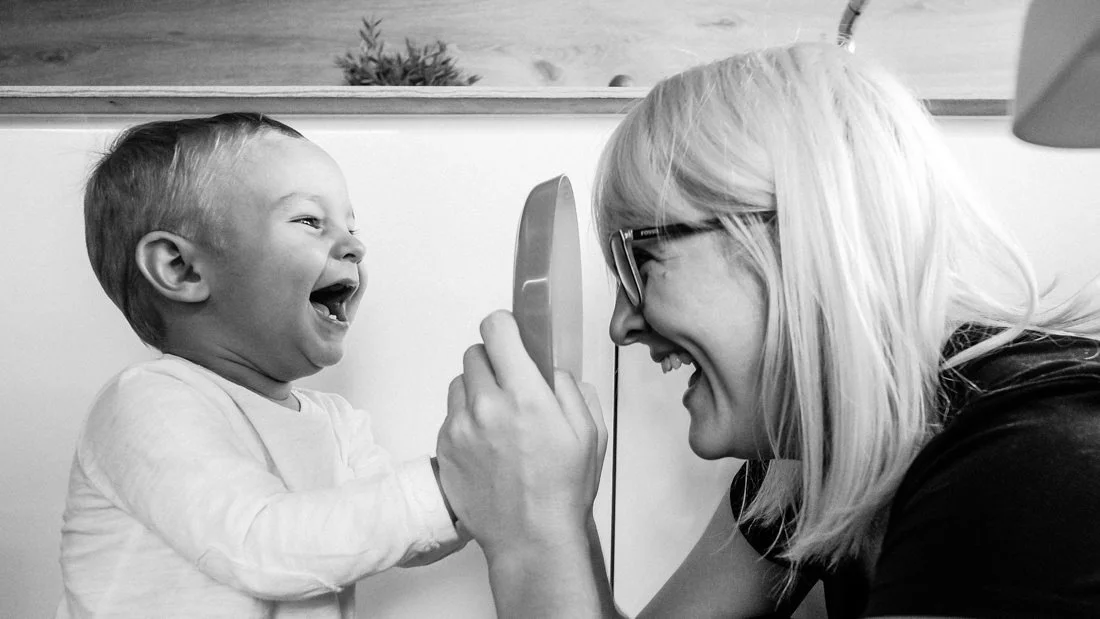 Madre e hijo riendo juntos en un momento familiar espontáneo en blanco y negro en casa