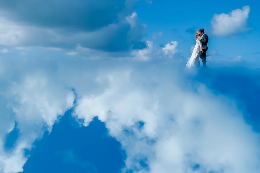 Bride and groom embracing in a dreamy blue-sky destination wedding, captured with emotional documentary photography across Europe