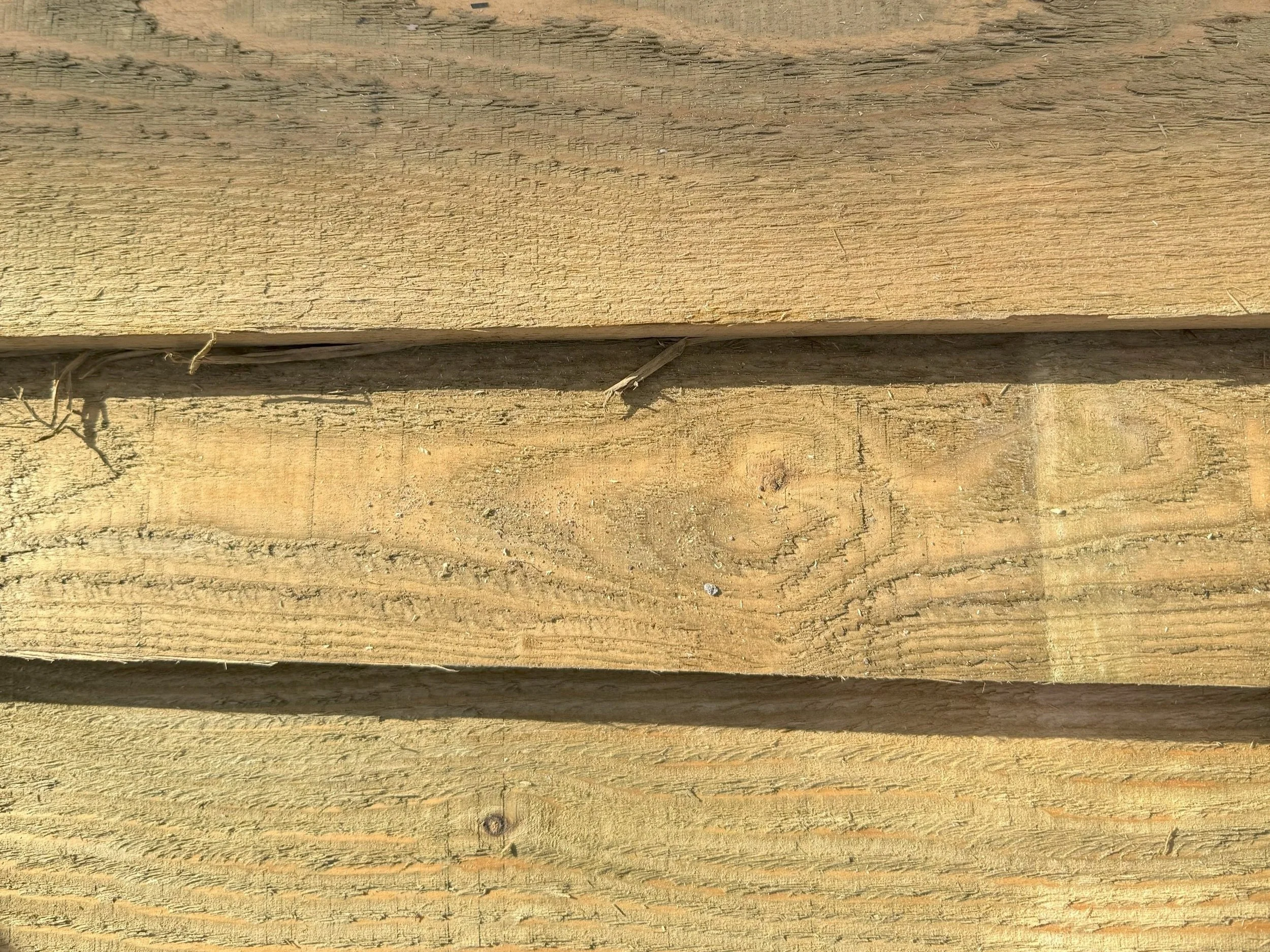 Close-up view of wooden planks with grain patterns and some small cracks, arranged horizontally.