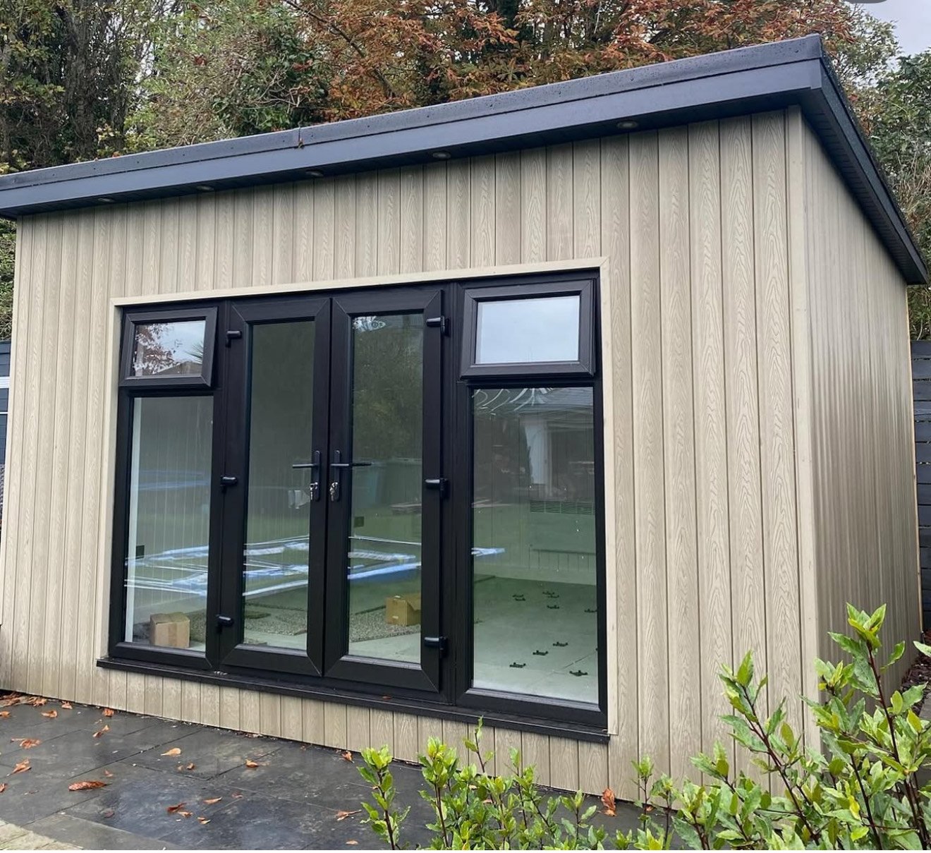 Composite garden room in light stone with wall of glass doors and windows