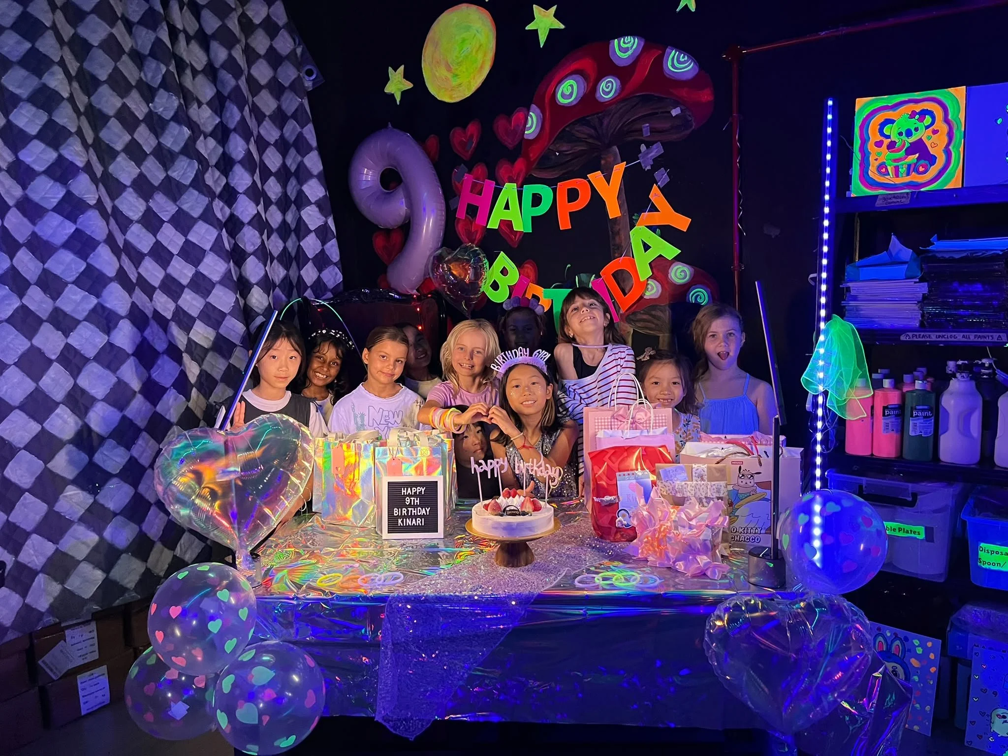 Family celebrating a child's 5th birthday with a cake, colorful decorations, and a 'Happy Birthday' banner in the background.