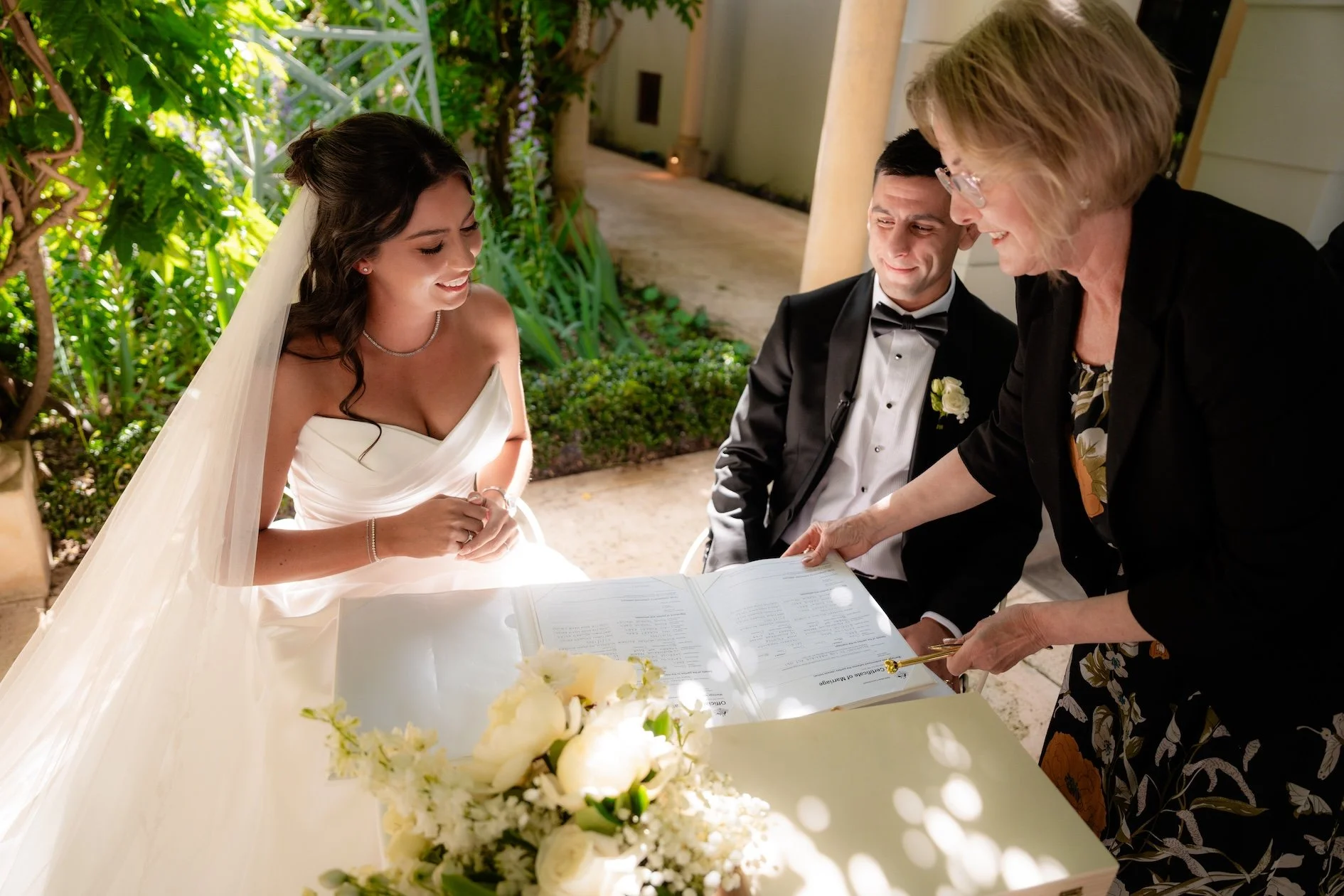 Bride and groom and marriage celebrant signing paperwork