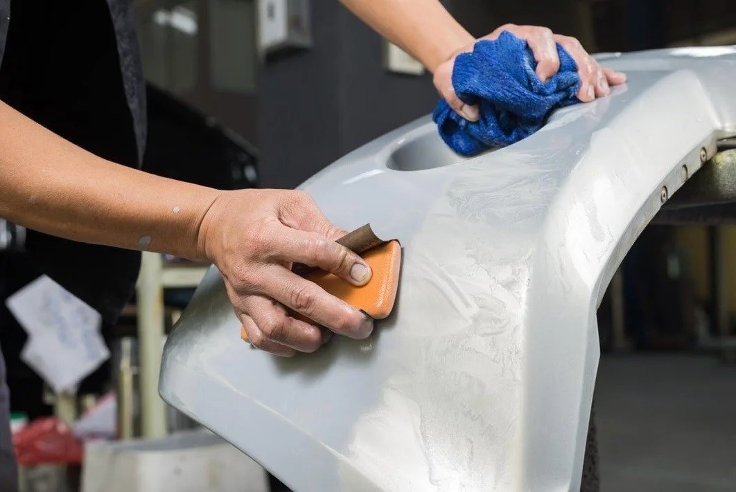 Person polishing a car bumper with a cloth and sandpaper in a workshop. Hydrographics WA, Western Australia's premier hydro dipping specialist