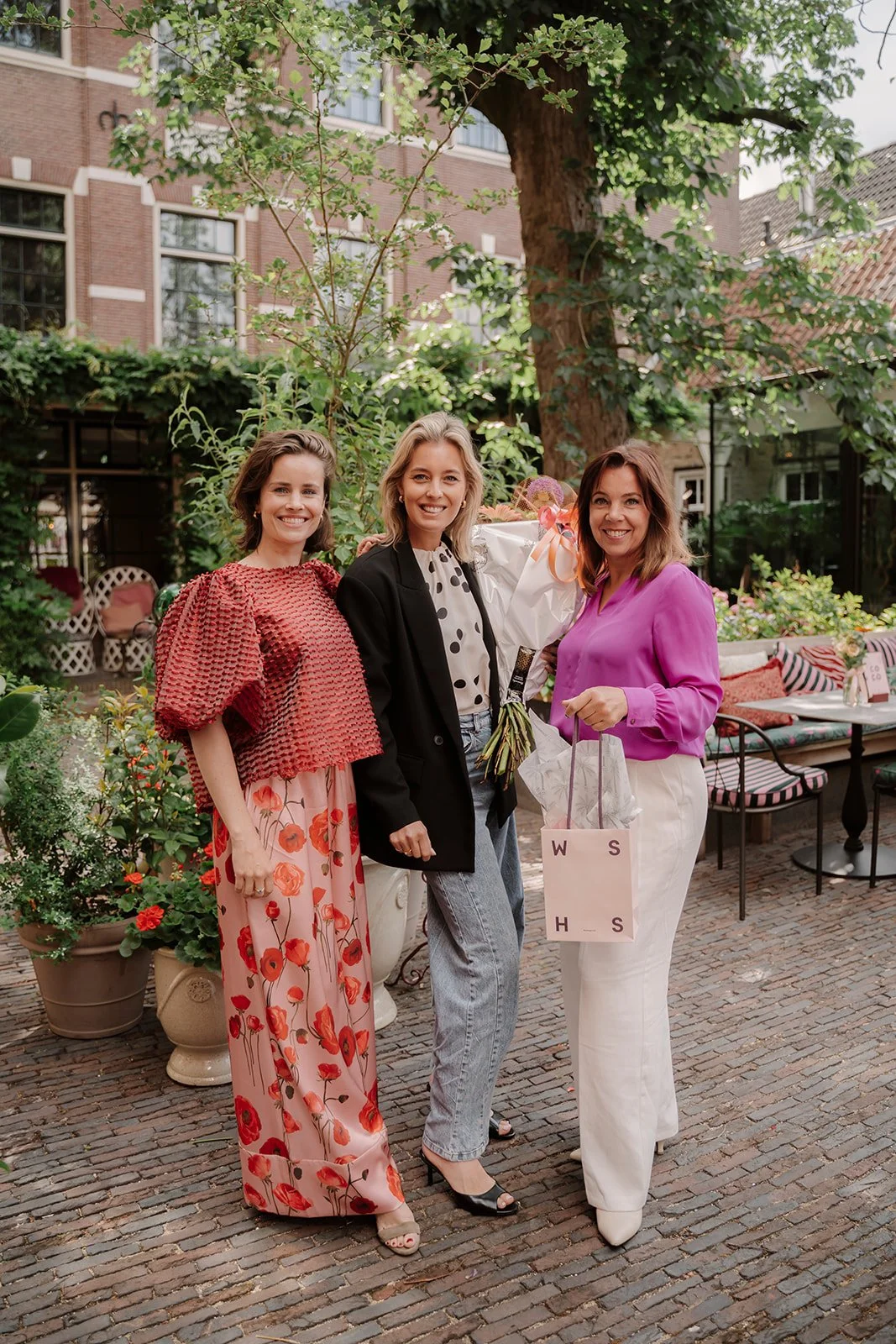 Drie vrouwen, ondernemers Sharon van Gestel (WSHS), Mariëlle Smit (SJUMO) en Lindy Bremer (BeBold Academy) lopen op een binnenplaats van het Weeshuis in Gouda.