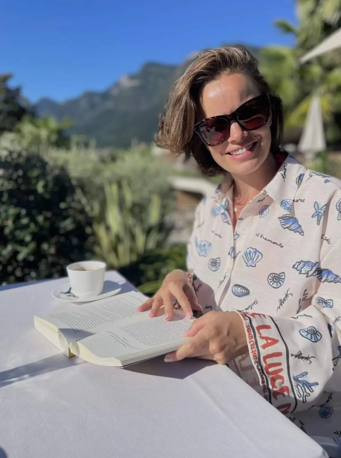 Jonge vrouw, Lindy Bremer, leest een boek aan een tafel in een subtropische omgeving.