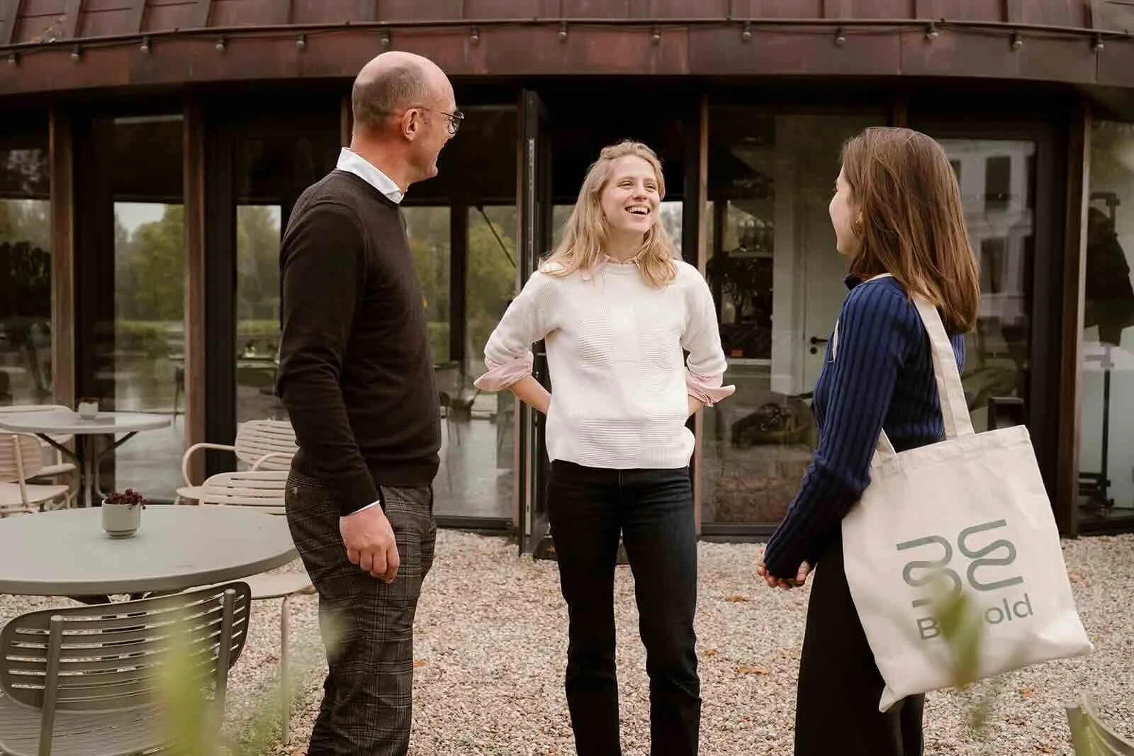 Drietal mensen die buiten staan tijdens een pauze van een BeBold Academy workshop en met elkaar lachen en praten voor een moderne Orangerie aan de Vecht bij Hotel Flora Batava.