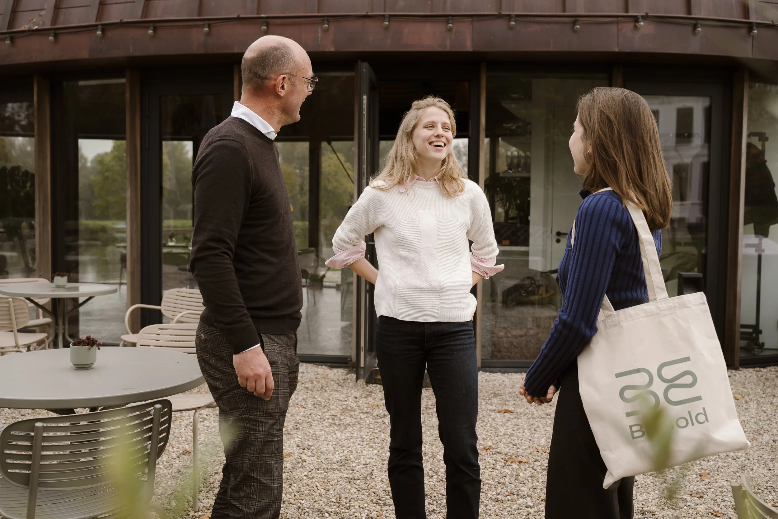 Twee mensen zitten in een gezellige ruimte bij een raam, ze maken een praatje en drinken koffie. Dit tijdens de pauze van een training over persoonlijk leiderschap.