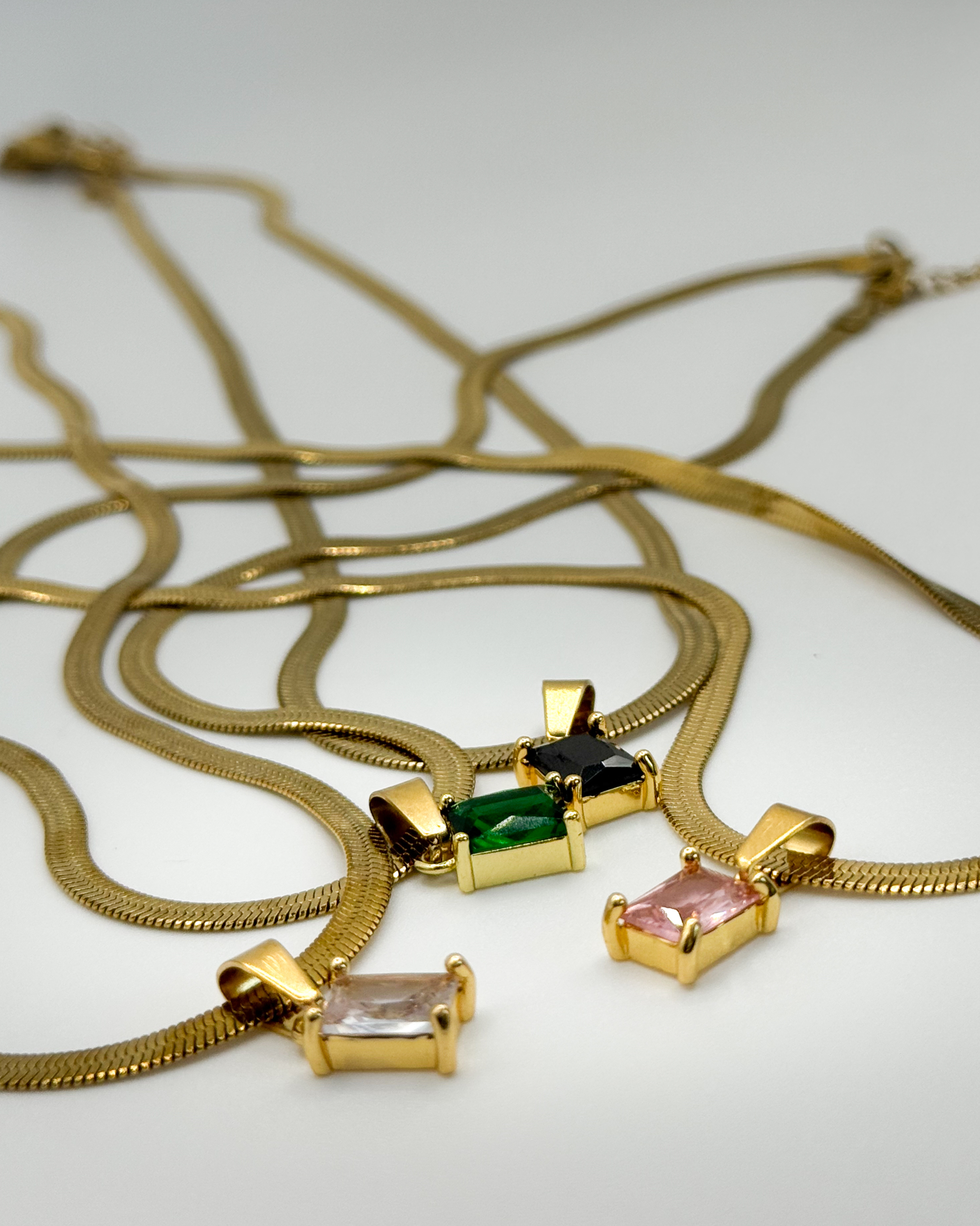 Close-up of the Fern necklace by Emilia Burk – gold waterproof chain with emerald-cut pendant available in green, black, pink, or clear.