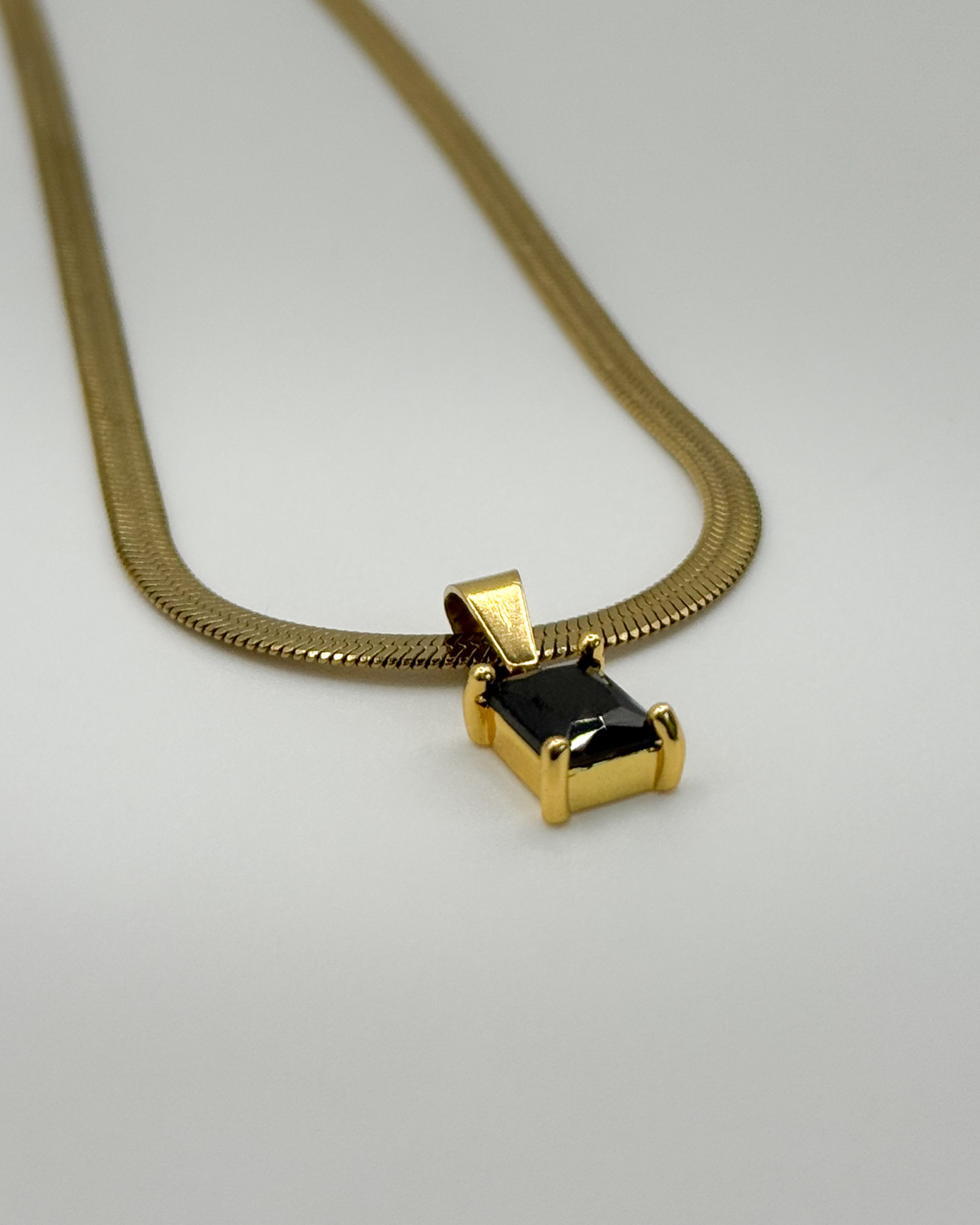 Close-up of the Fern necklace by Emilia Burk – gold waterproof chain with emerald-cut pendant available in green, black, pink, or clear.