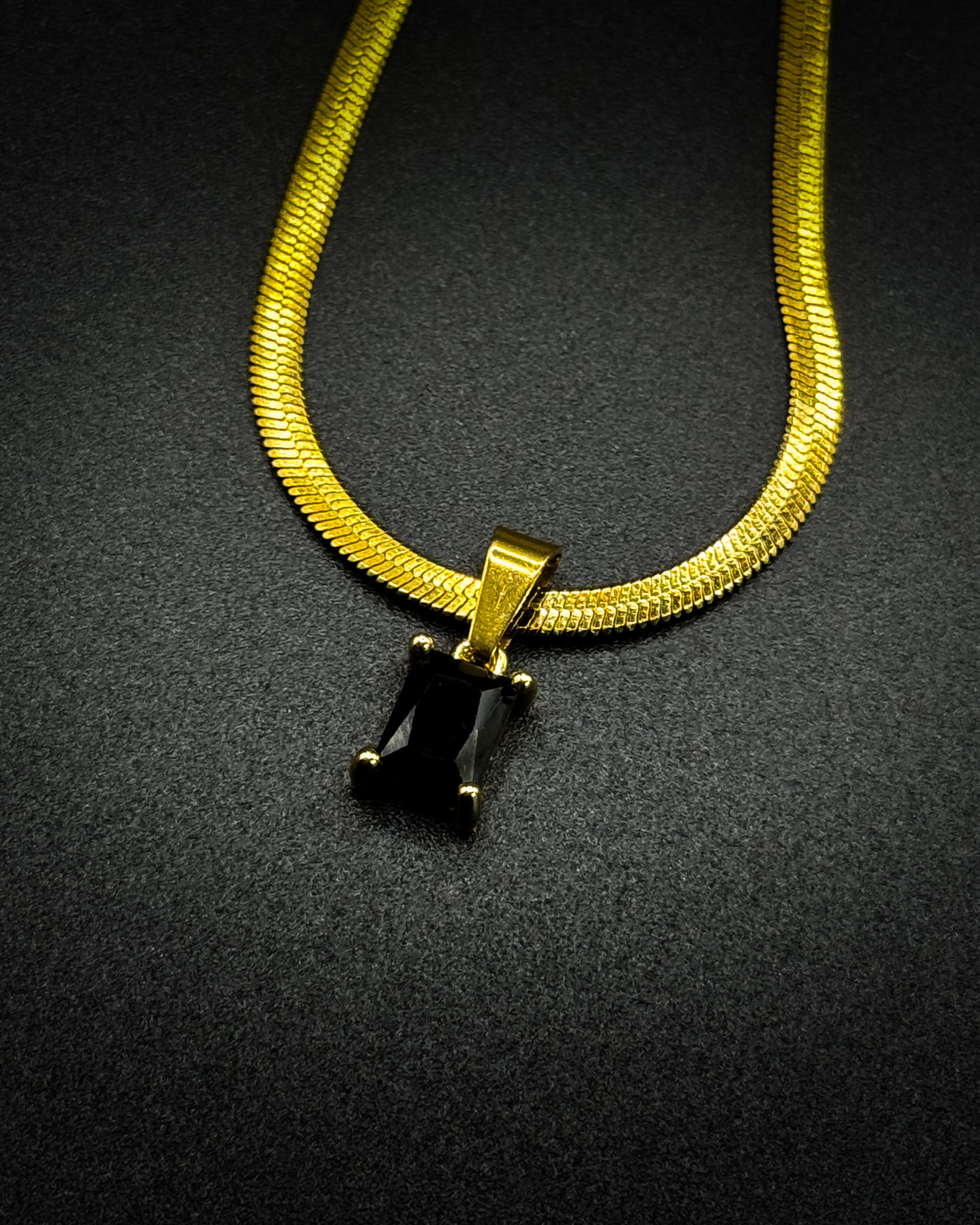 Close-up of the Fern necklace by Emilia Burk – gold waterproof chain with emerald-cut pendant available in green, black, pink, or clear.