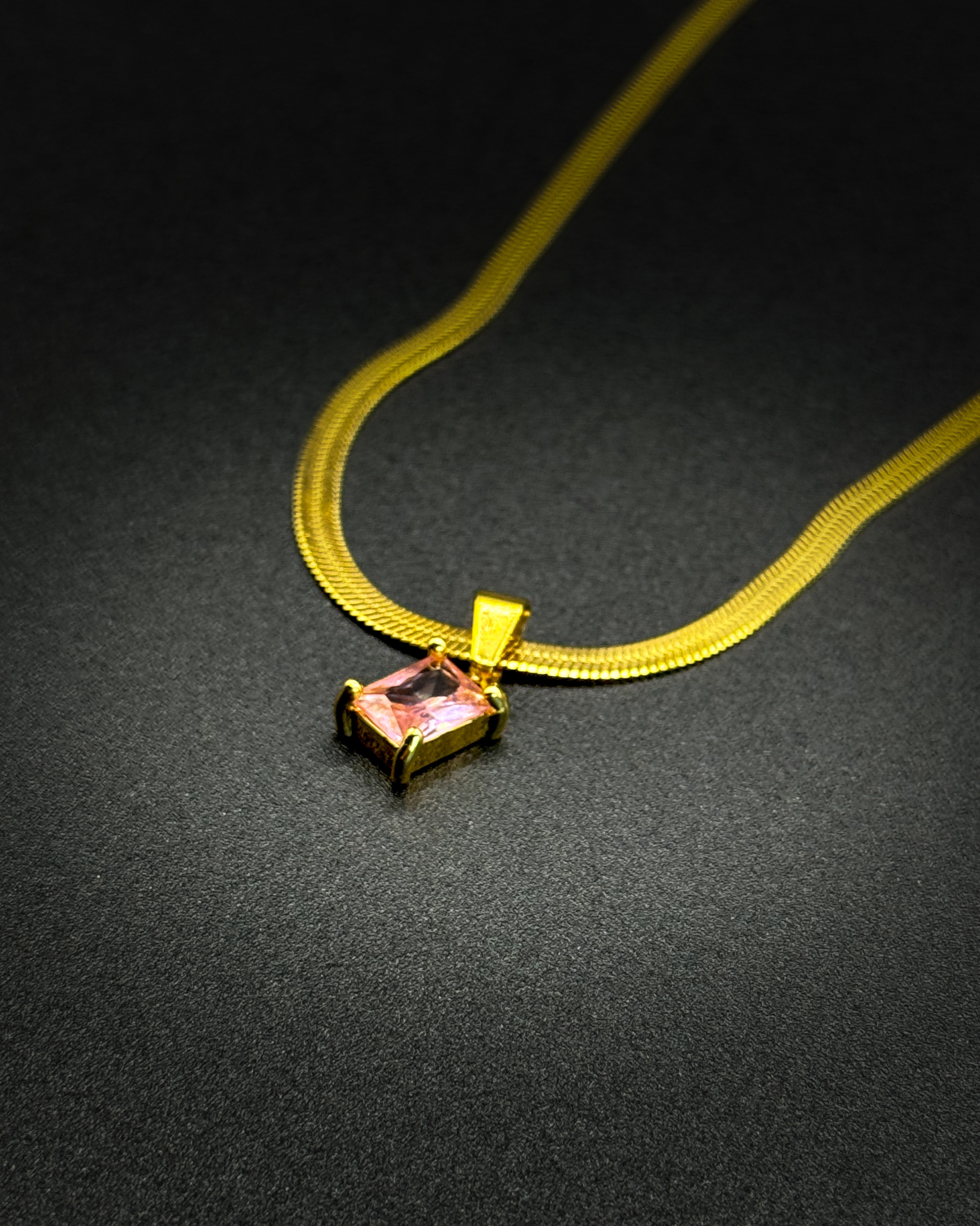 Close-up of the Fern necklace by Emilia Burk – gold waterproof chain with emerald-cut pendant available in green, black, pink, or clear.