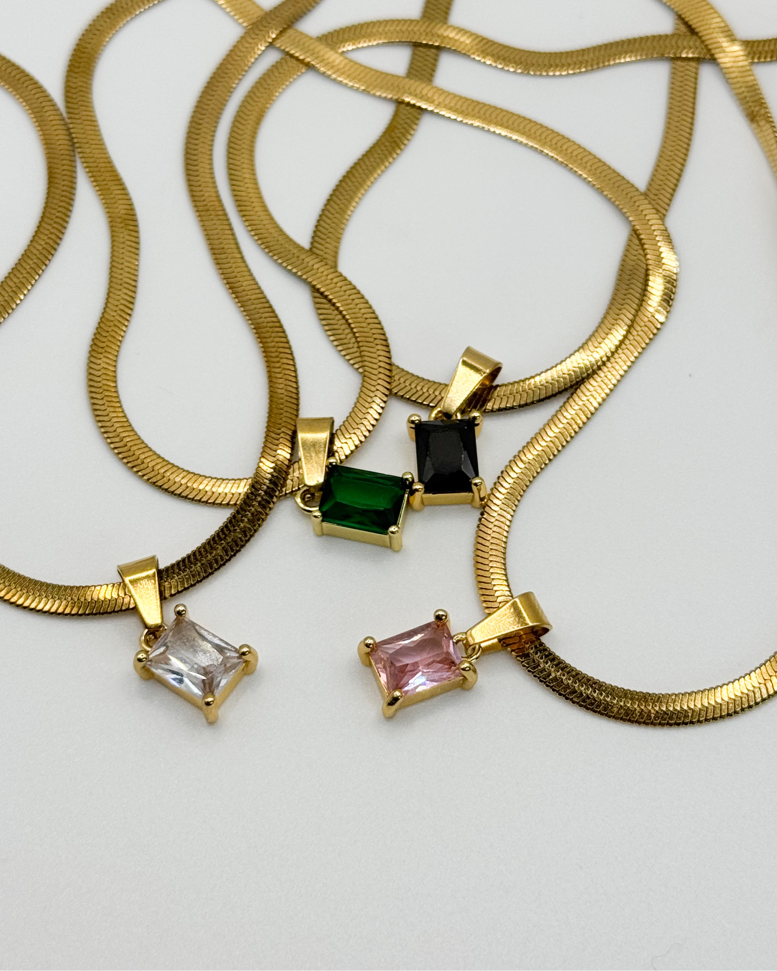 Close-up of the Fern necklace by Emilia Burk – gold waterproof chain with emerald-cut pendant available in green, black, pink, or clear.