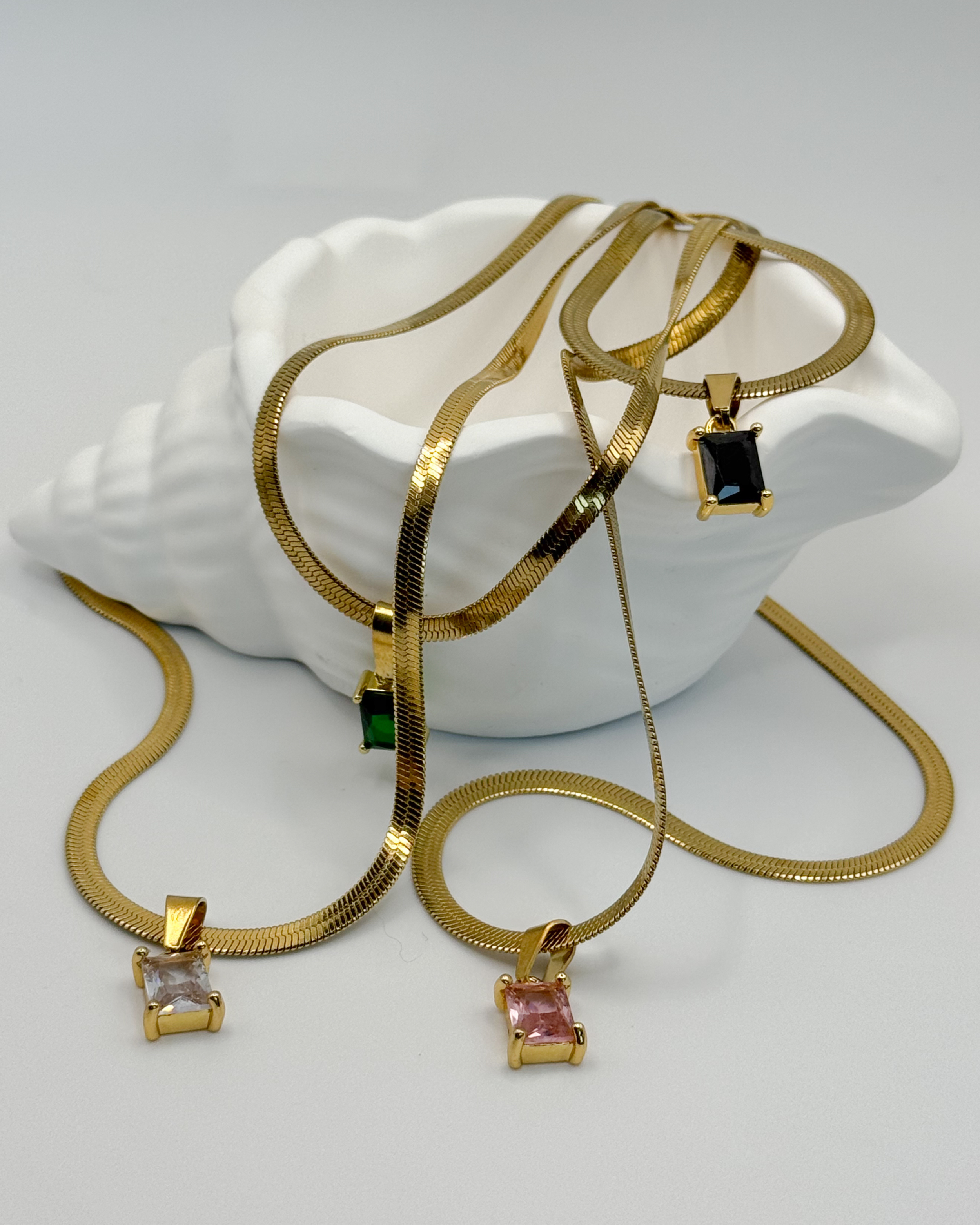Close-up of the Fern necklace by Emilia Burk – gold waterproof chain with emerald-cut pendant available in green, black, pink, or clear.
