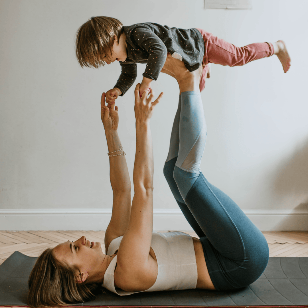 A woman doing yoga while balancing her child on her feet.