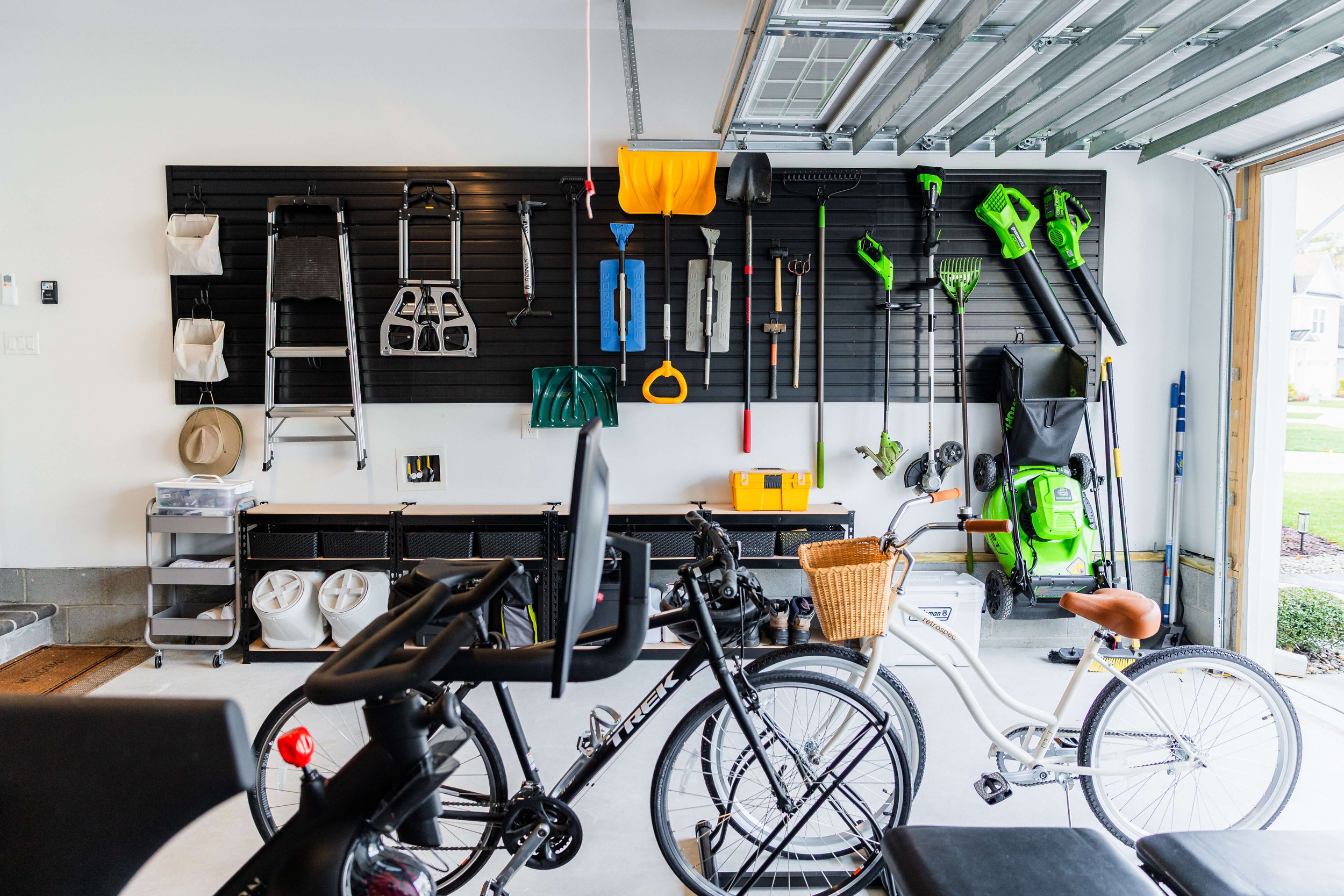 Wall-mounted slatwall storage keeping rakes and shovels neatly organized in a residential garage.