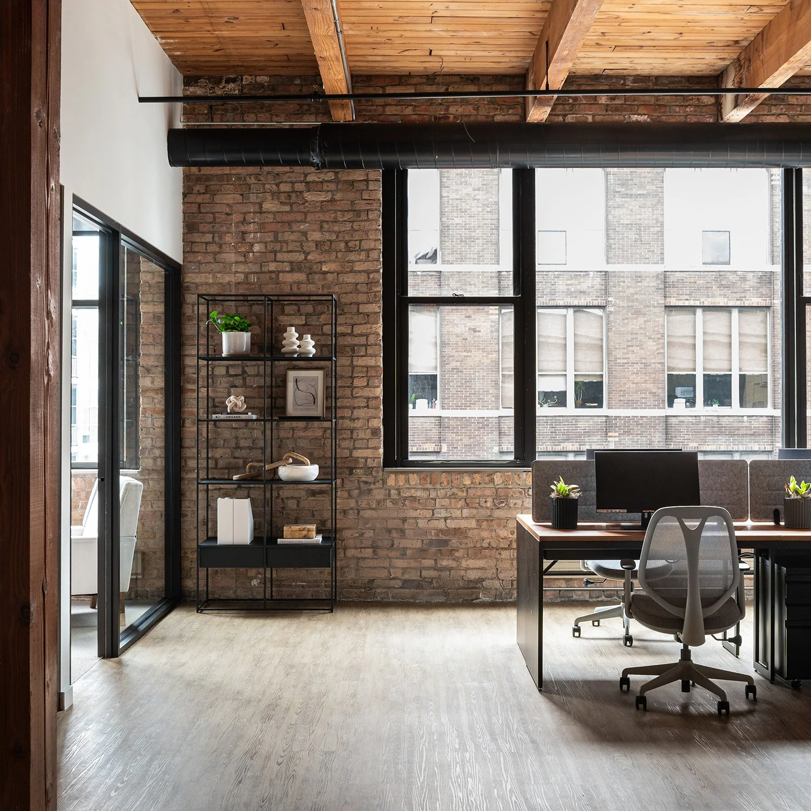 Bookshelf styled against an exposed brick wall with desk cubbies in a Chicago executive office.