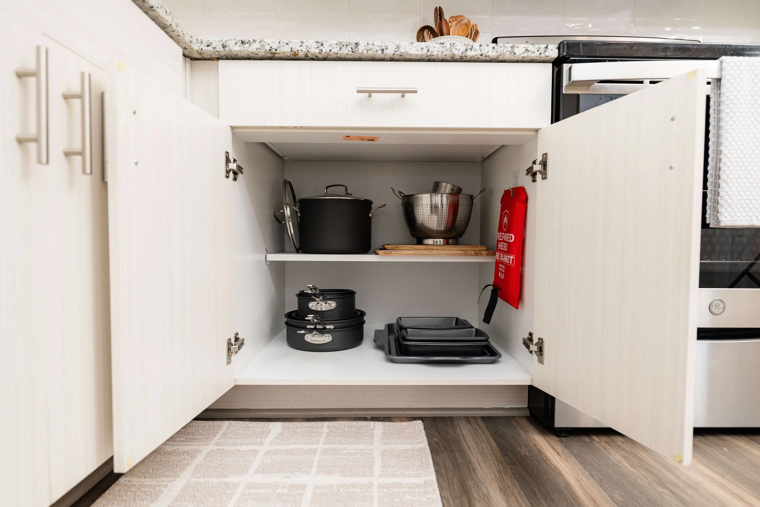 Thoughtfully organized pots and pans in a coastal kitchen cabinet, blending function with five-star resort-inspired style.